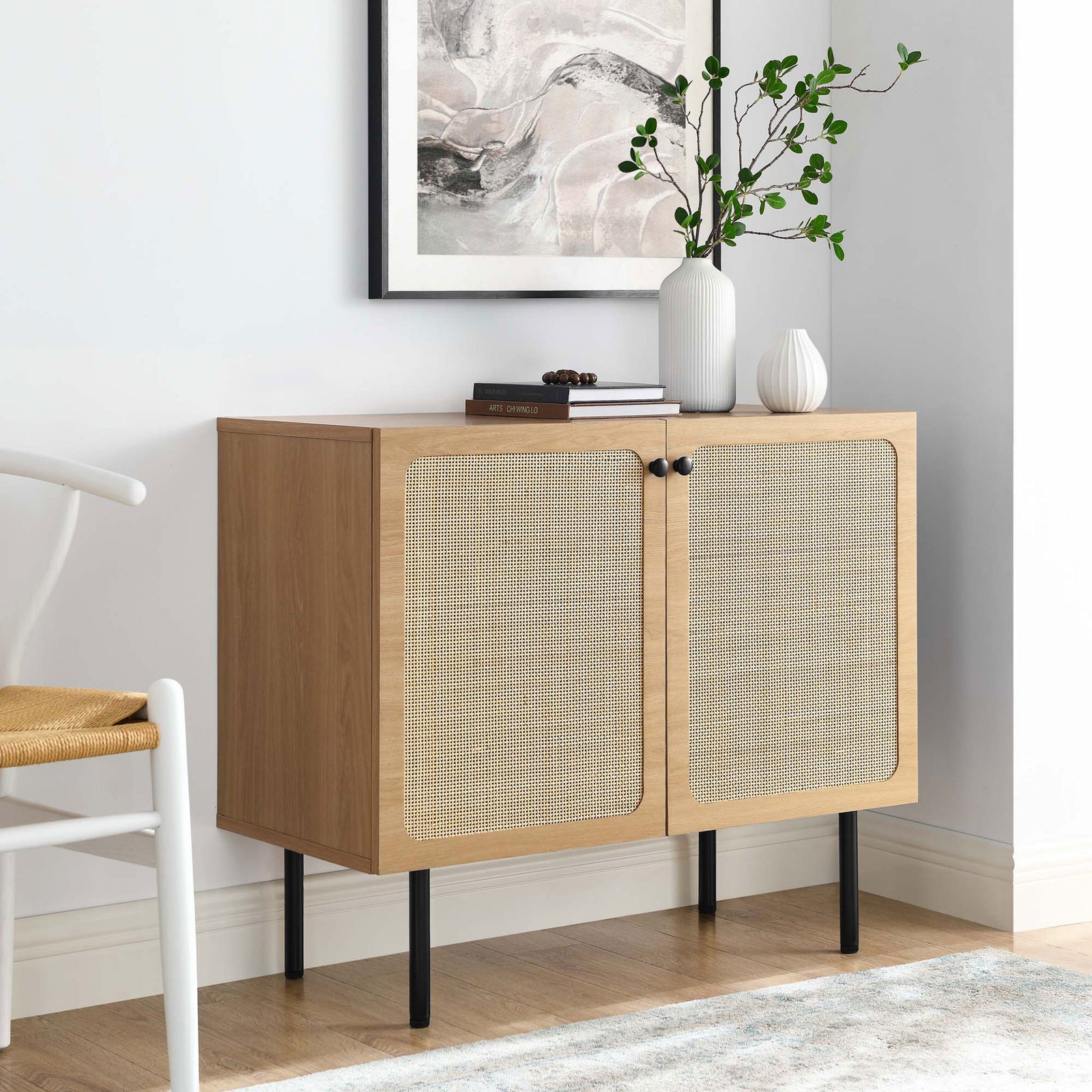 Oak rattan accent cabinet styled in a cozy living room with artwork, greenery, and decor || EEI-6200-OAK || front_angle_room