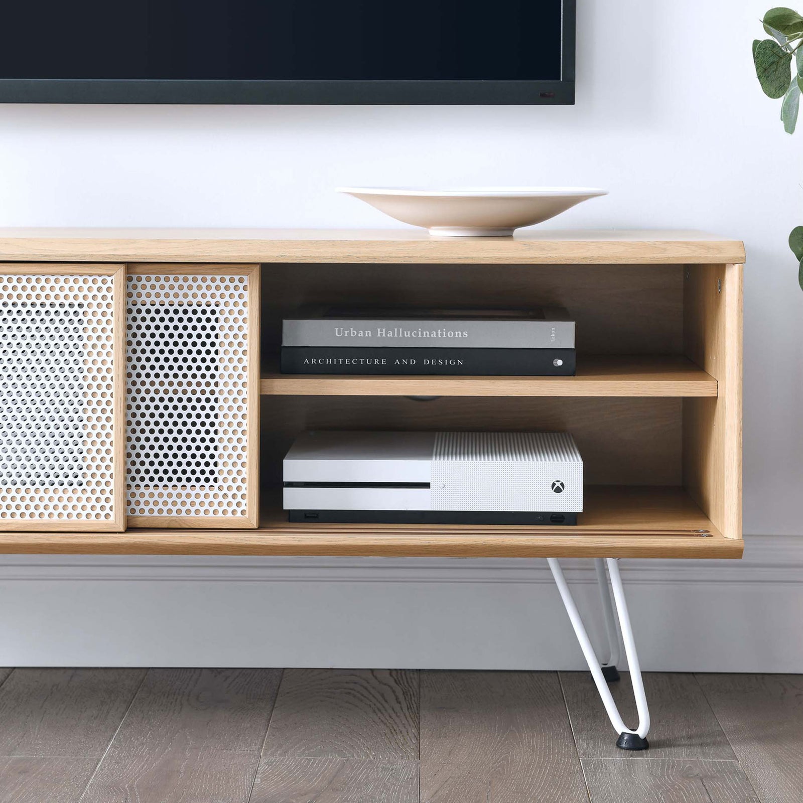Oak TV stand styled in a living room, showing open shelving for game consoles and books next to the mesh doors || EEI-6202-OAK || storage_room
