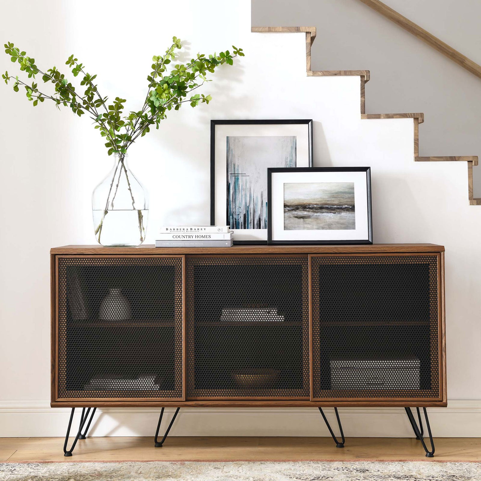 Walnut sideboard styled with artwork and greenery, adding modern warmth beneath a staircase. || EEI-6204-WAL || front_room