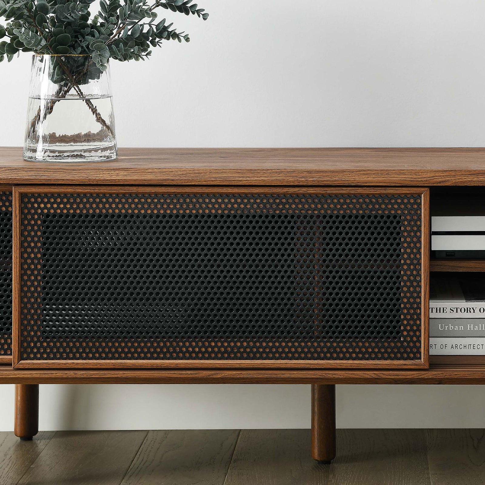 Styled walnut TV stand with vase and books, showing textured mesh door and open storage shelf || EEI-6234-WAL || detail_room