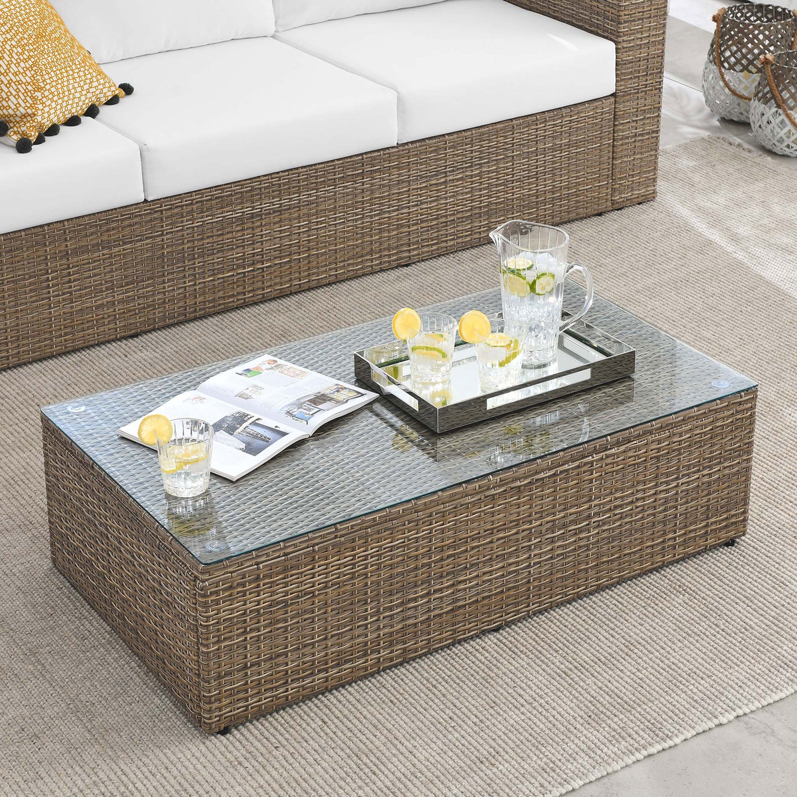 Brown wicker outdoor coffee table with glass top paired with matching sectional seating on patio || EEI-6239 || front_angle_room
