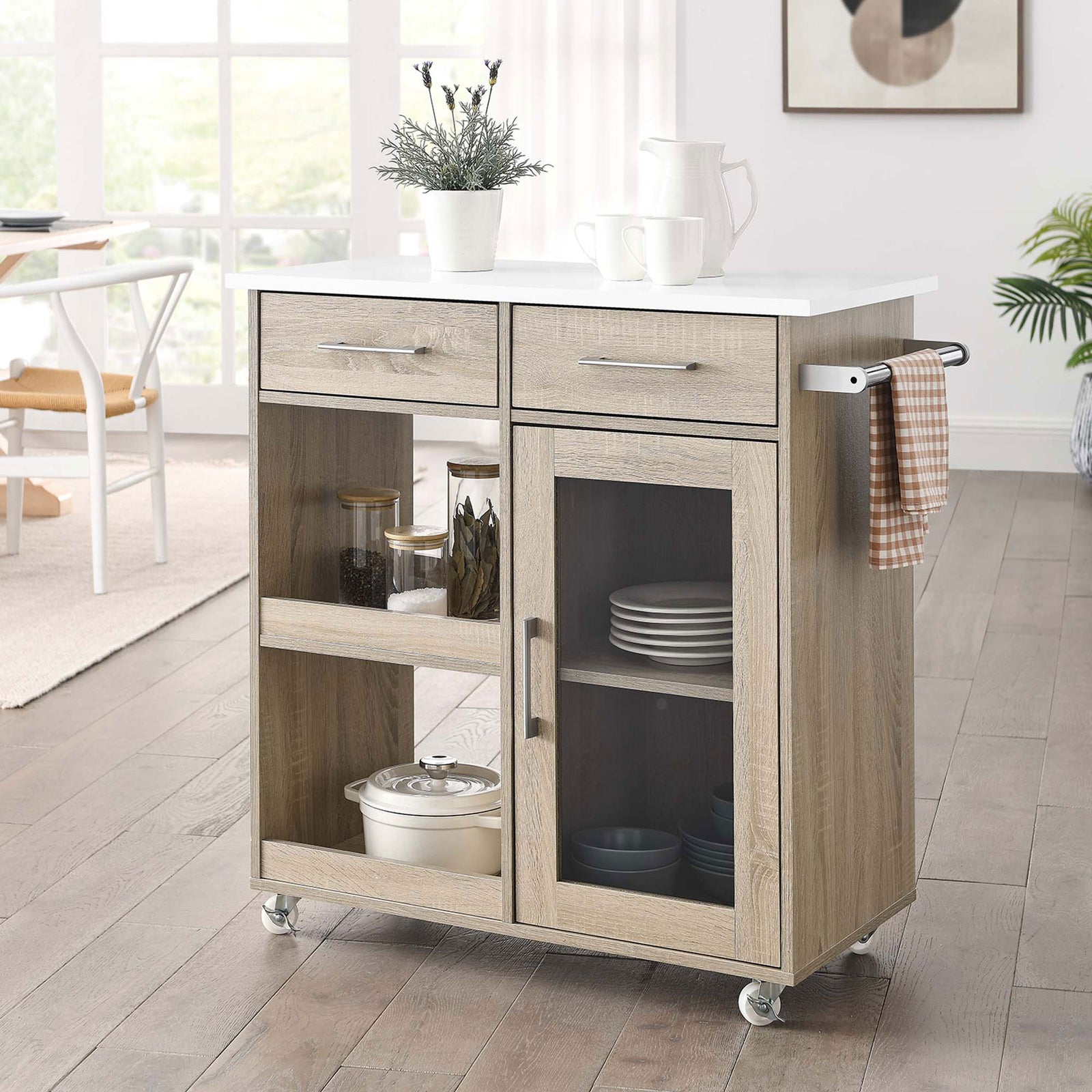 Oak and white kitchen cart styled in a bright dining space with open shelves, glass-door cabinet, and side towel bar || EEI-6275-OAK-WHI || front_angle_room