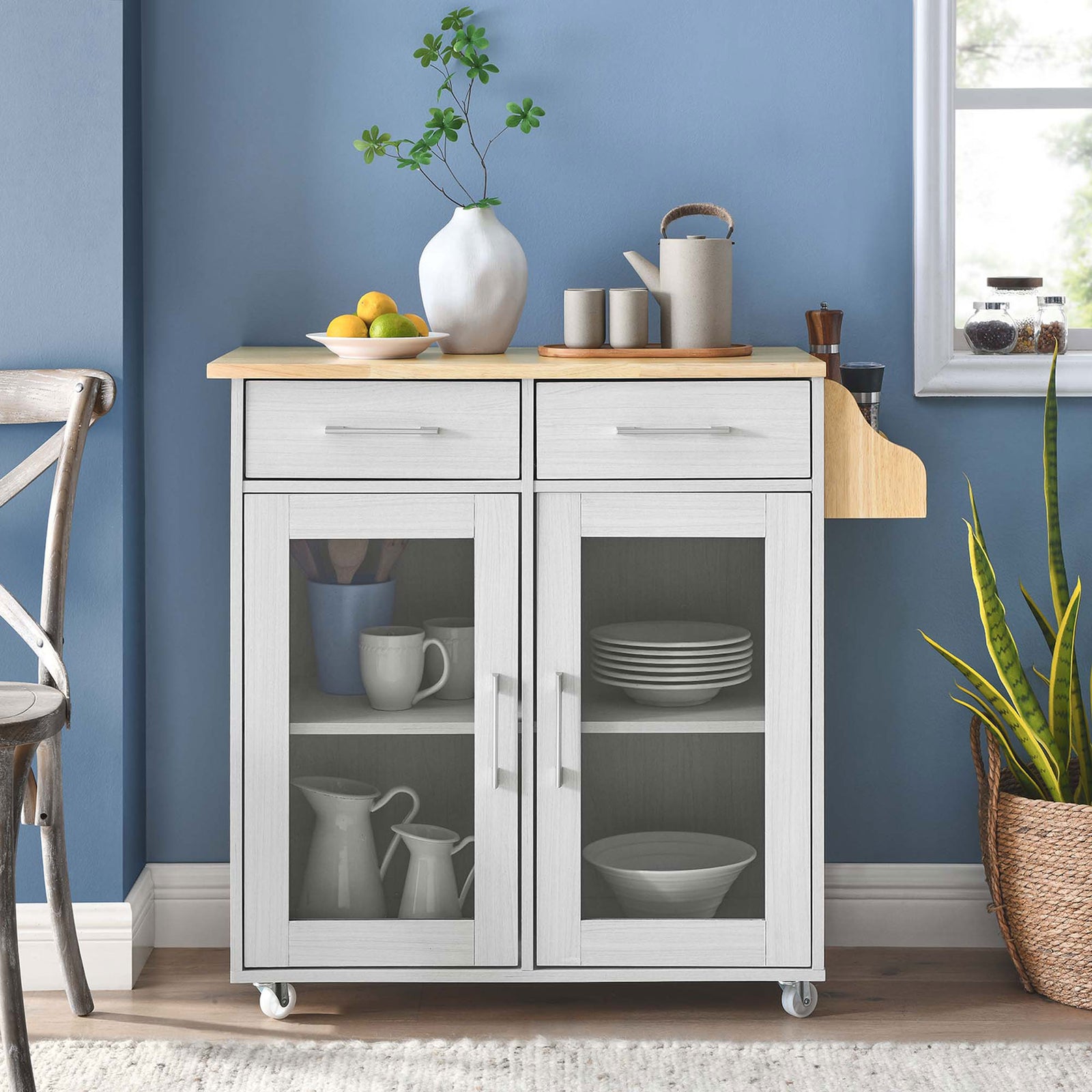 White kitchen cart styled in a modern dining space with dinnerware, plants, and warm wood accents || EEI-6276-WHI-NAT || front_room