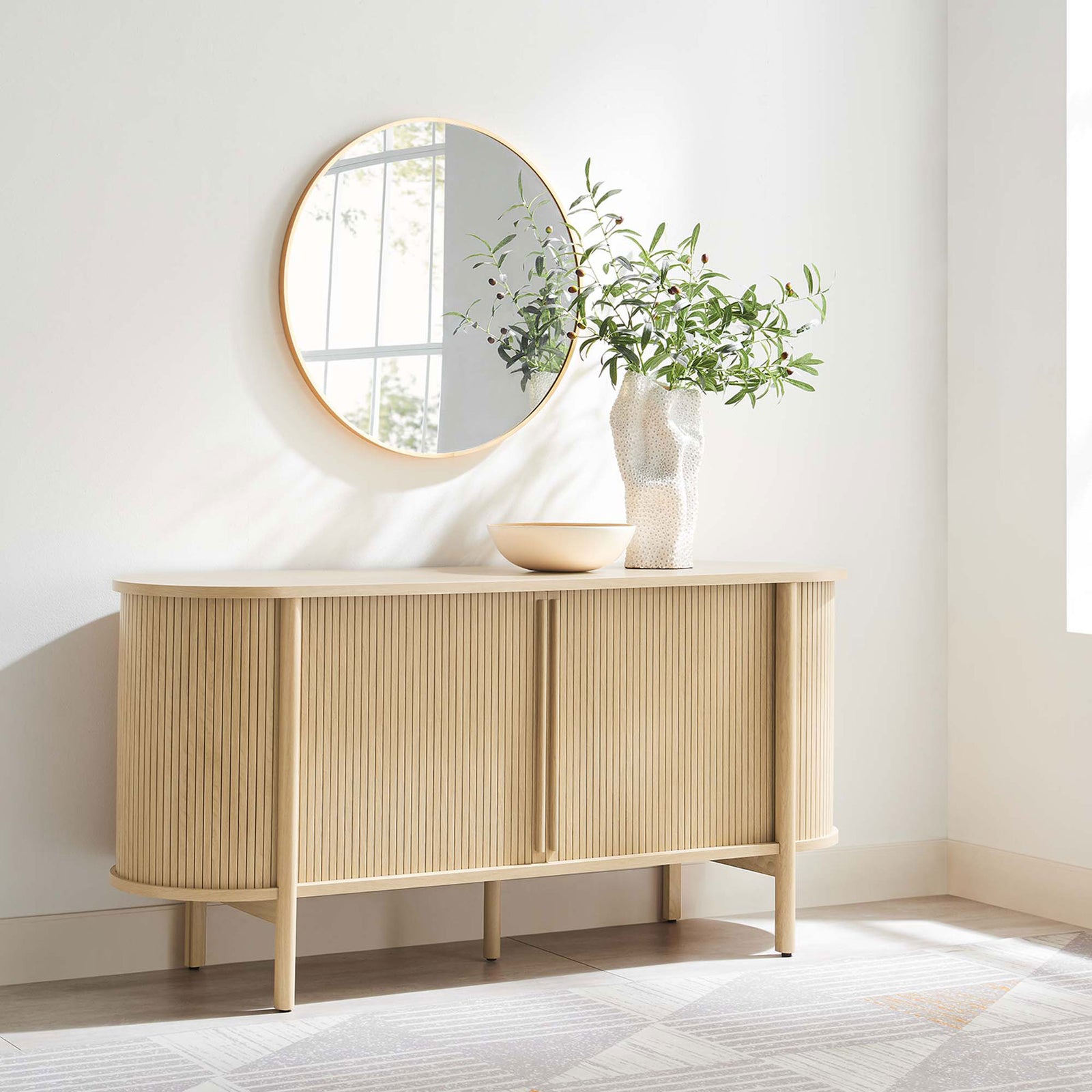 Curved oak sideboard styled in a bright entryway with round mirror, greenery, and soft neutral decor. || EEI-6309-OAK || front_angle_room