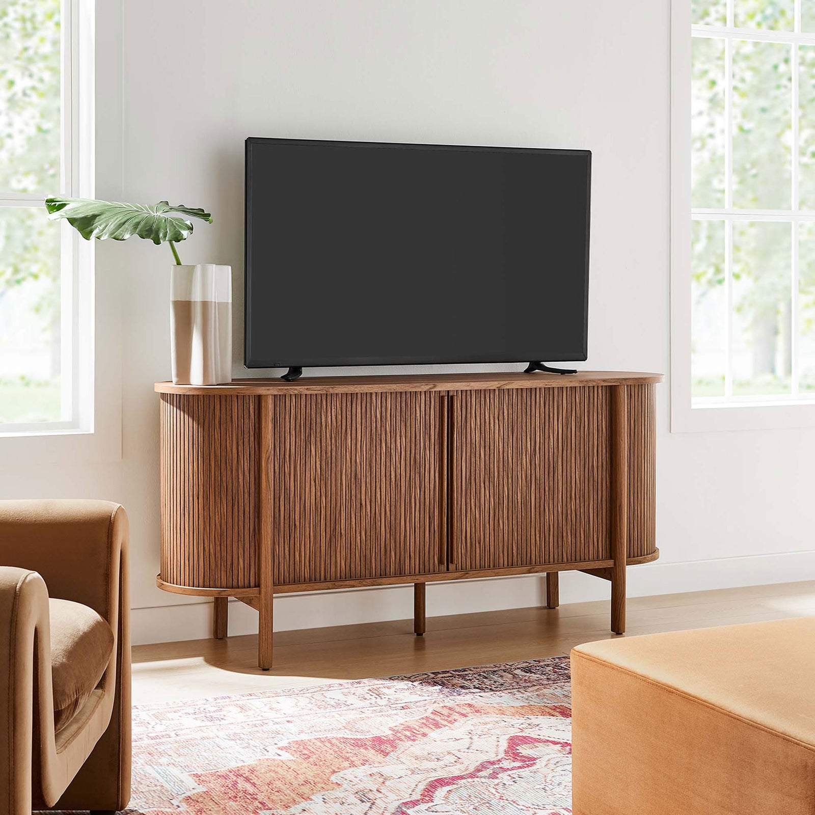 Curved fluted sideboard serving as a TV console in a bright living room with cozy modern decor || EEI-6309-WAL || front_angle_room