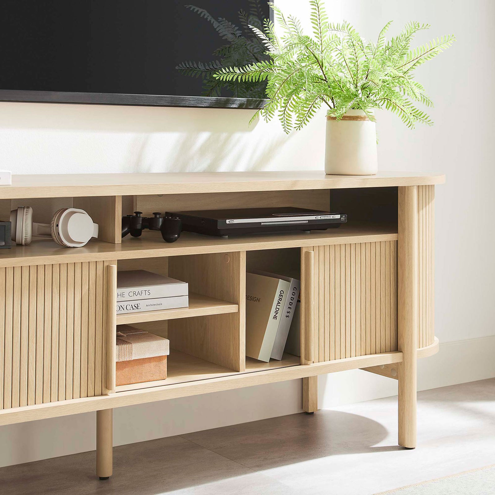 Oak Cadence TV cabinet styled with books, media gear, and greenery for everyday living room use. || EEI-6310-OAK || detail_room