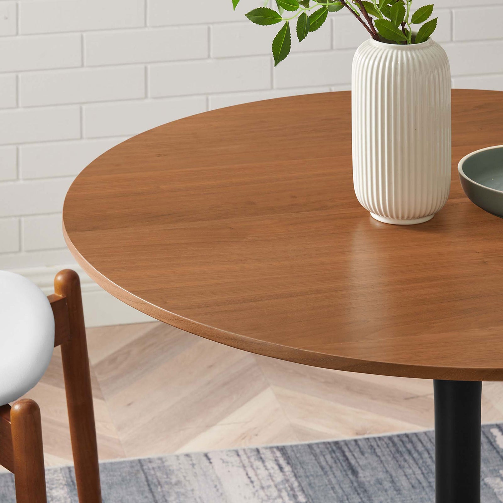 Walnut dining tabletop styled with decor, showing beveled edge and warm finish in a modern room. || EEI-6313-WAL-BLK || detail_room