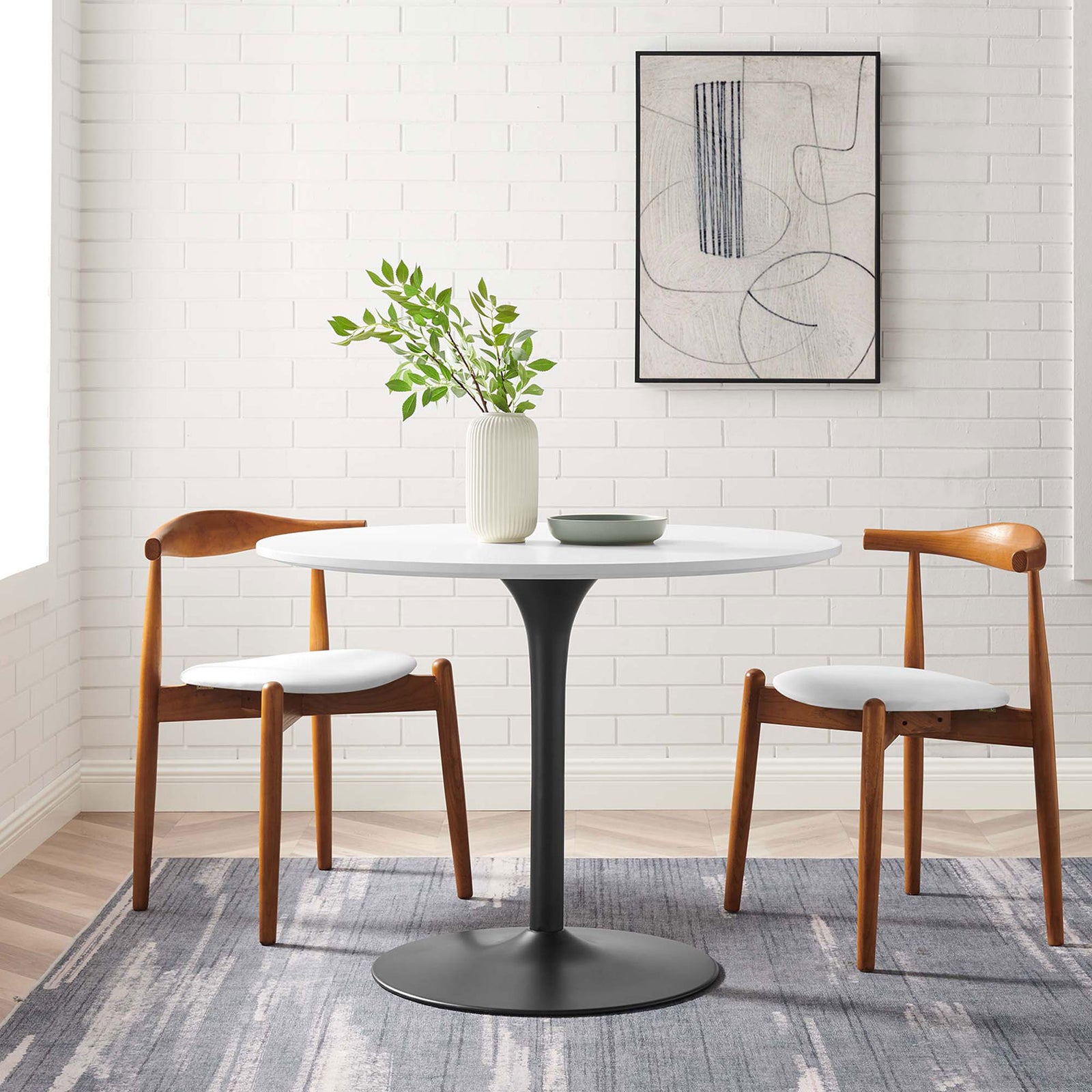 Round white and black dining table styled in a modern room with wood chairs and neutral decor || EEI-6313-WHI-BLK || front_room