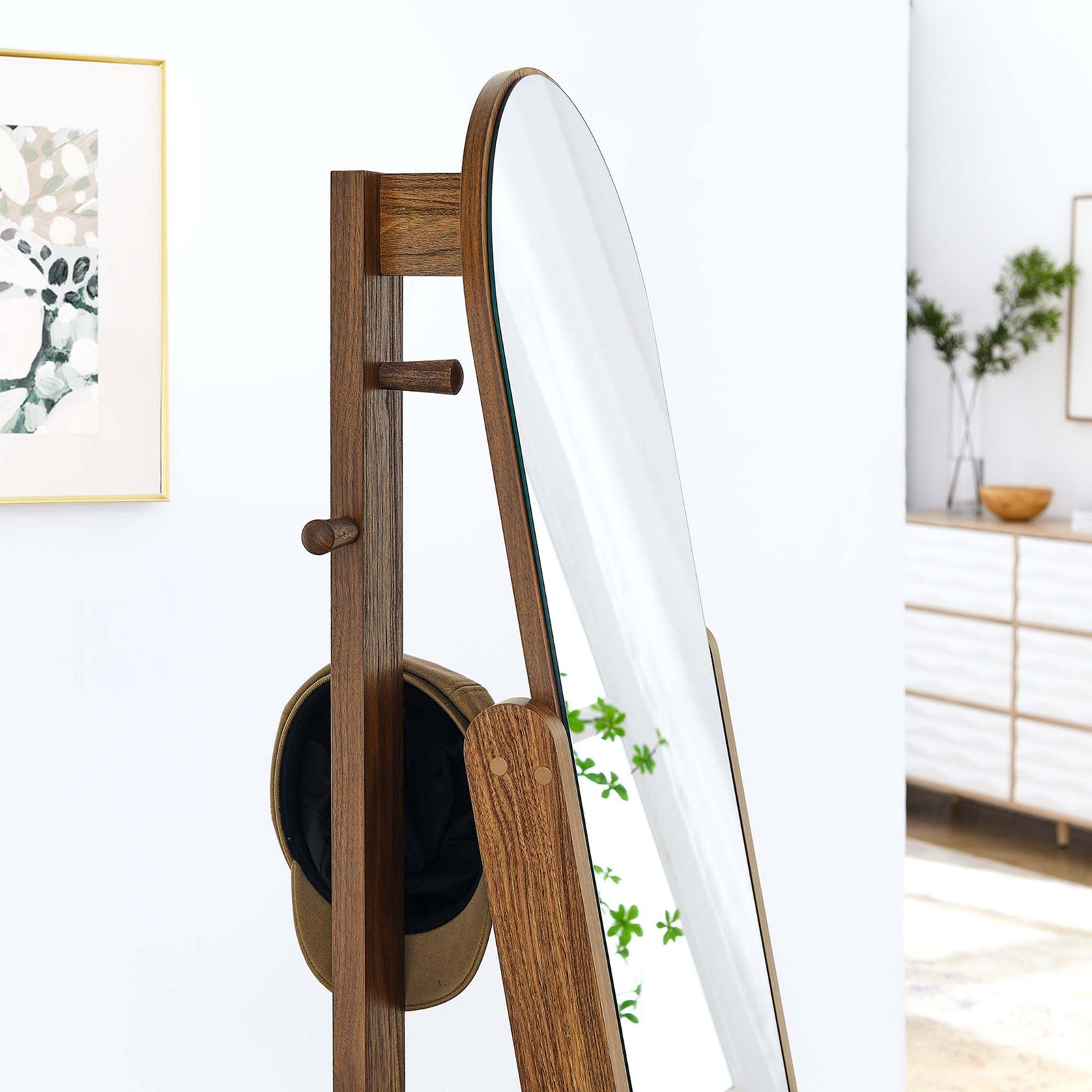 Walnut standing mirror in a bright room with side peg holding a hat and mirror reflecting leafy greenery || EEI-6346-WAL || detail_room