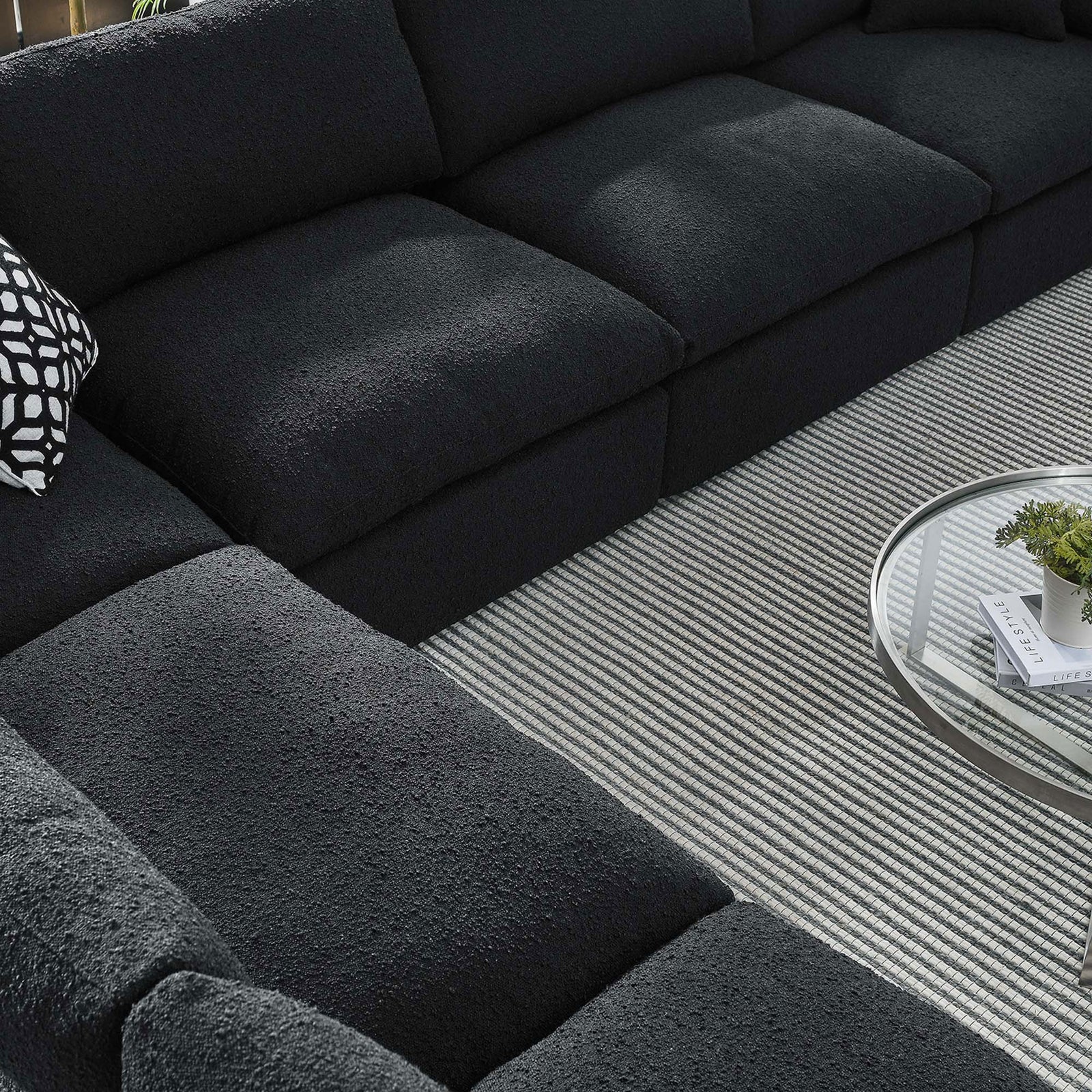 Textured black boucle cushions of the sectional styled with a striped rug and modern glass coffee table || EEI-6369-BLK || detail_room
