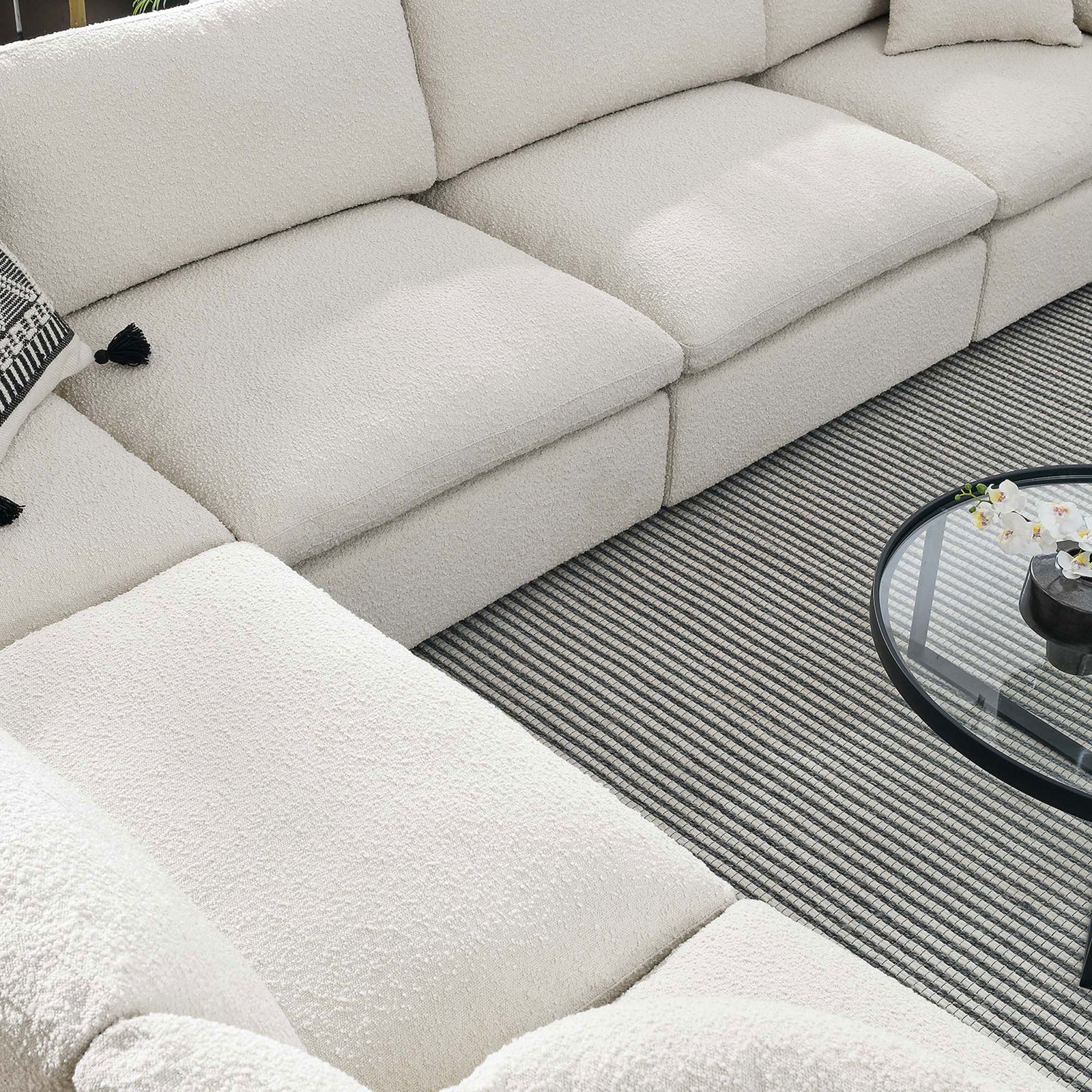 Ivory boucle sectional corner with textured seats layered over a striped area rug || EEI-6369-IVO || detail_room