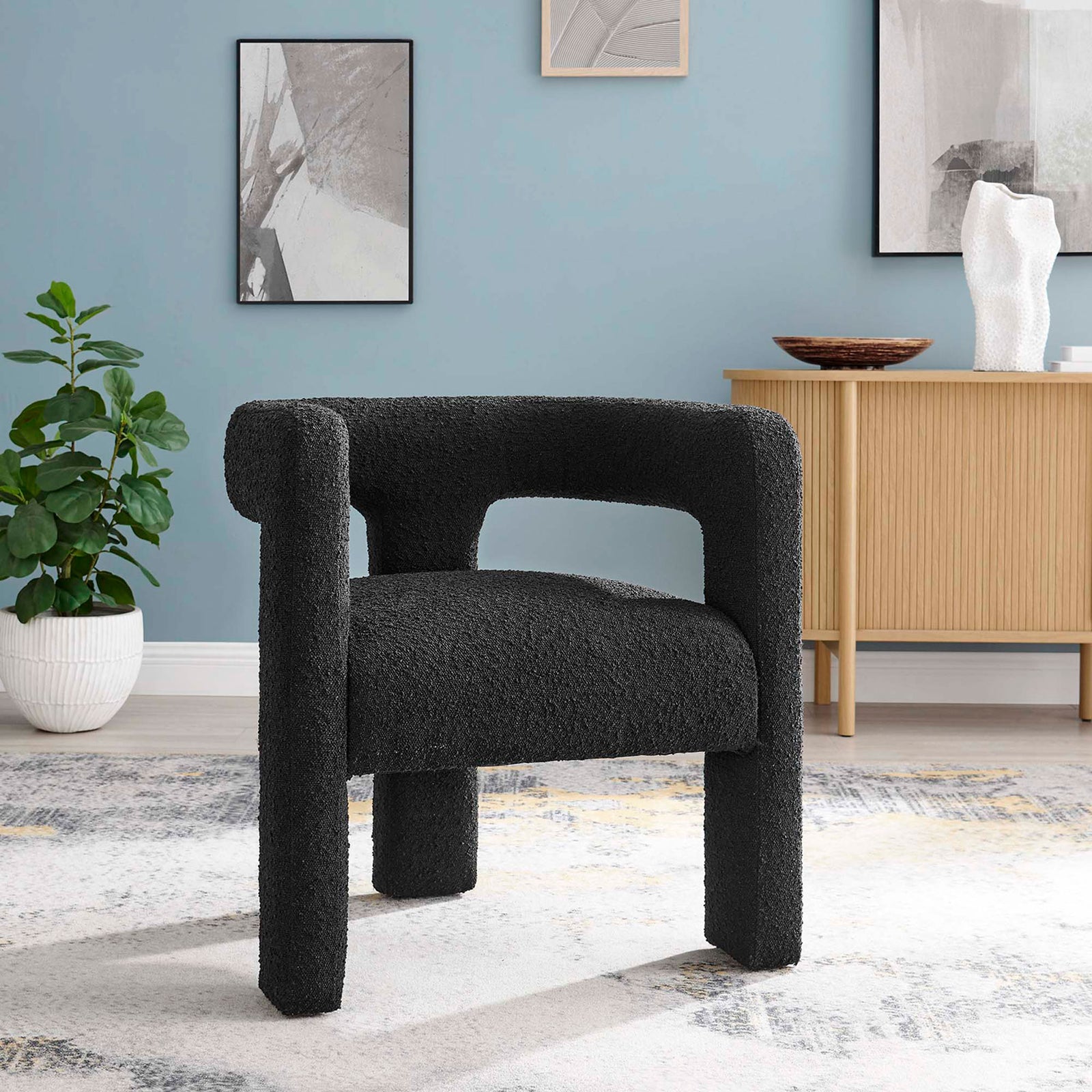 Sculptural armchair grounds the room with its curved open back and richly textured black boucle. || EEI-6479-BLK || front_room