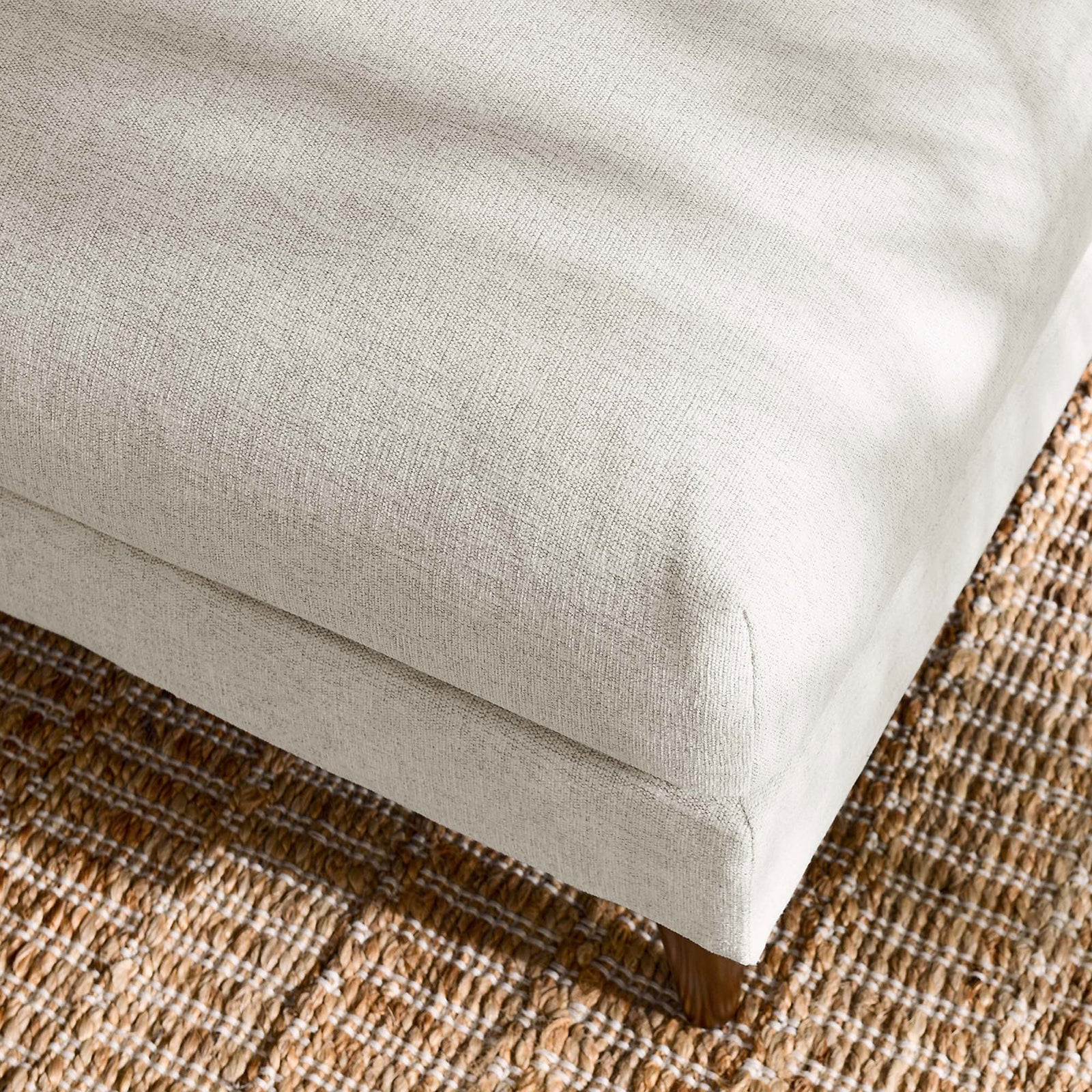 Textured ivory ottoman cushion resting on a natural woven rug for a relaxed, cozy living room look || EEI-6481-HEI || detail_room