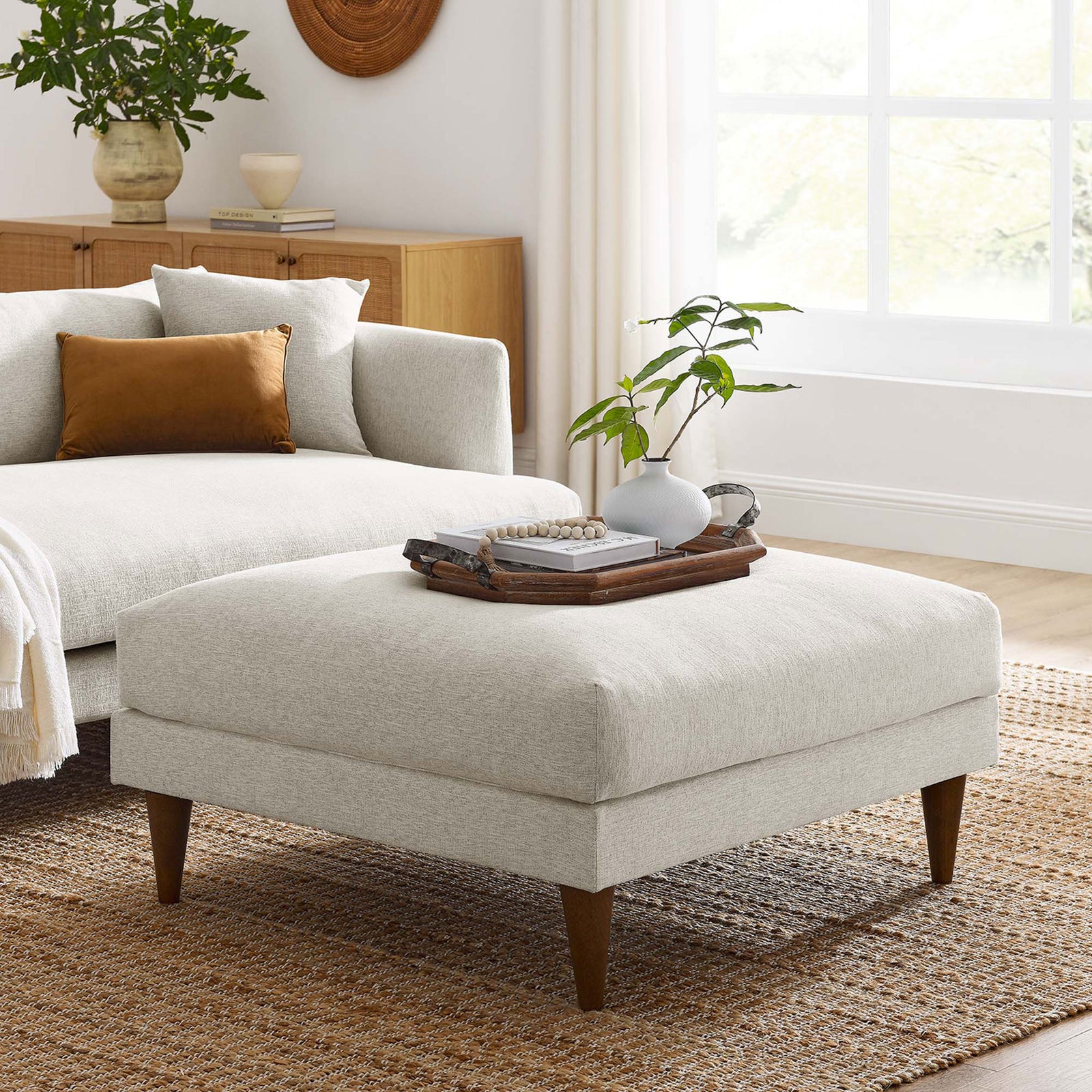 Ivory ottoman styled in a bright living room, paired with a matching sofa and tray for versatile lounging || EEI-6481-HEI || front_angle_room
