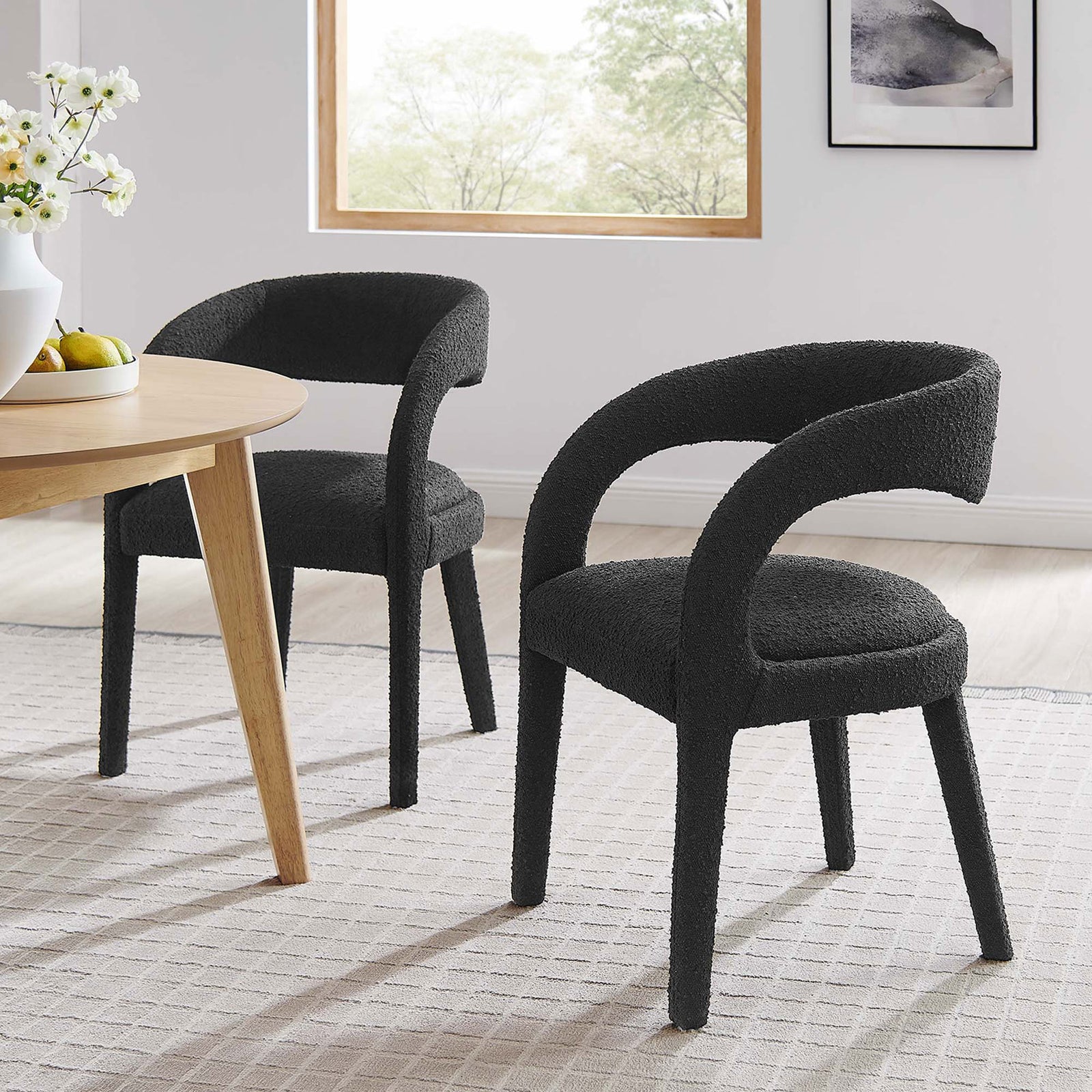Set of two black boucle dining chairs around a modern wood table, creating an inviting contemporary dining space. || EEI-6562-BLK || front_angle_multi_room