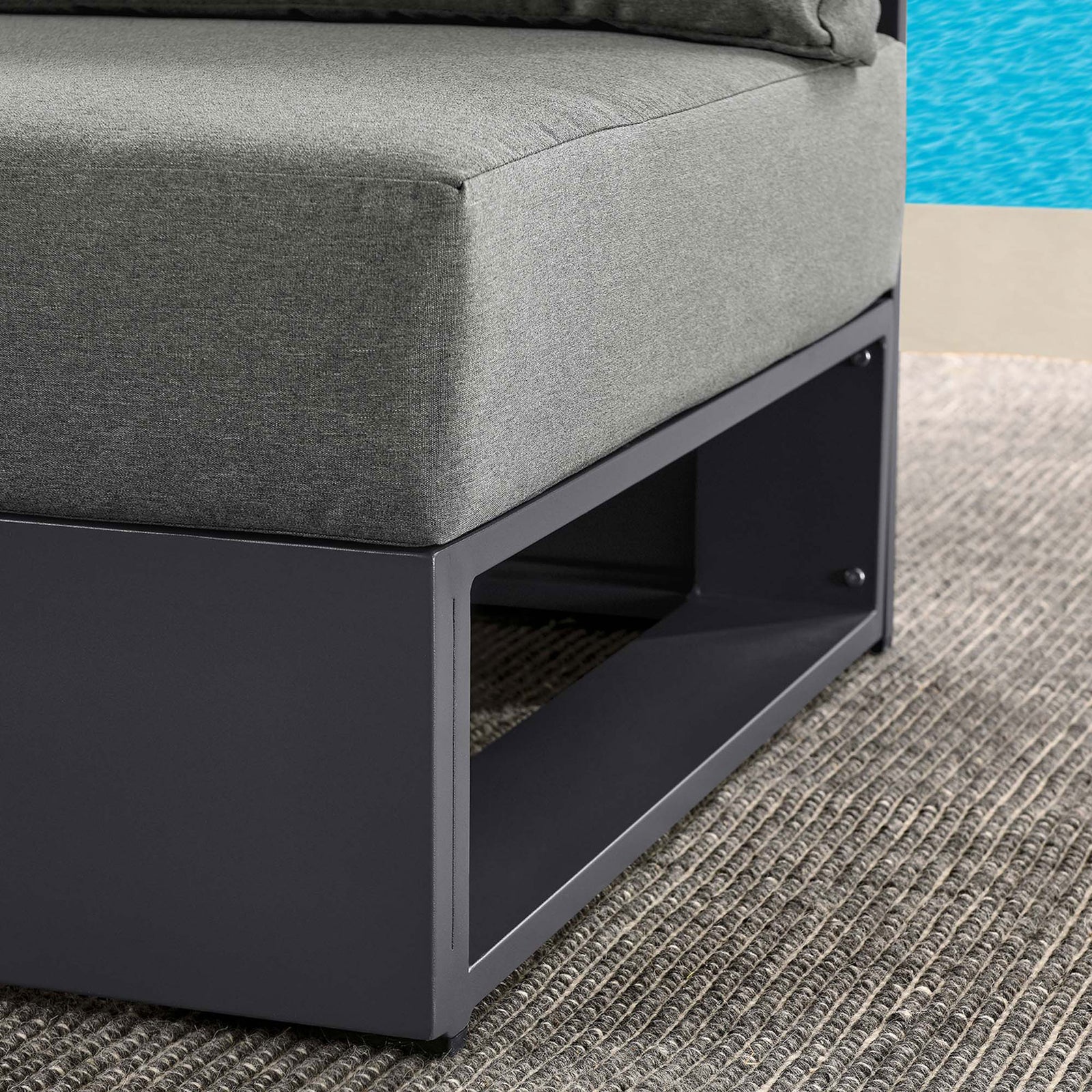 Charcoal cushion and dark base of the Tahoe armless chair styled on a textured outdoor rug beside the pool || EEI-6628-GRY-CHA || detail_room