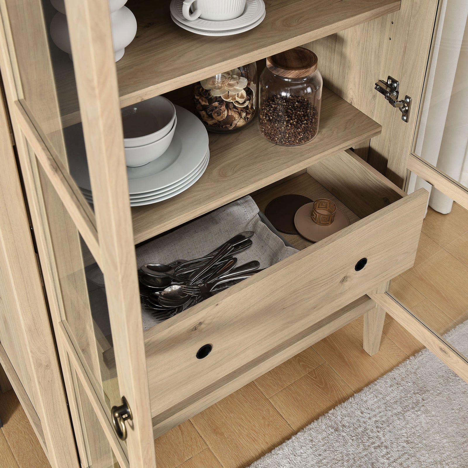 Lower drawer of the light oak cabinet storing dishes, textiles, and everyday serveware || EEI-6639-LOA || storage_open_room