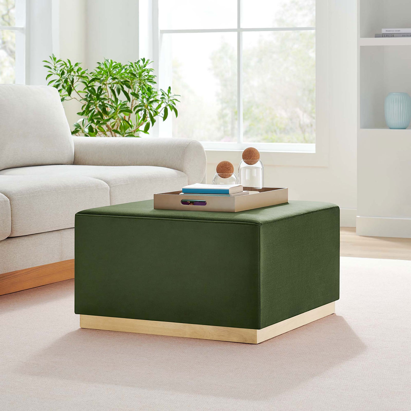 Moss green velvet ottoman centers a bright modern living room, pairing naturally with neutral sofa and greenery || EEI-6643-MOG-NAT || front_angle_room