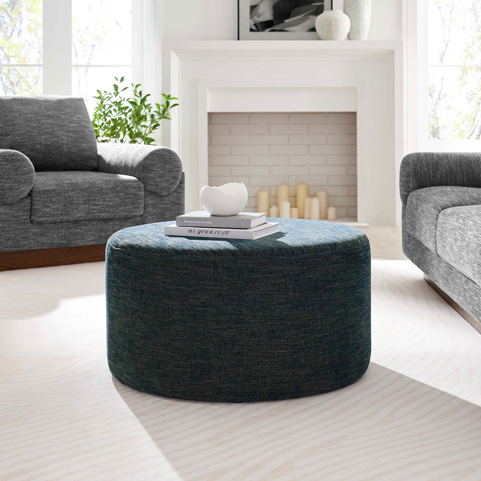 29 inch azure ottoman styled as a living room coffee table with books and decor on a light rug || EEI-6647-HEA || front_angle_room