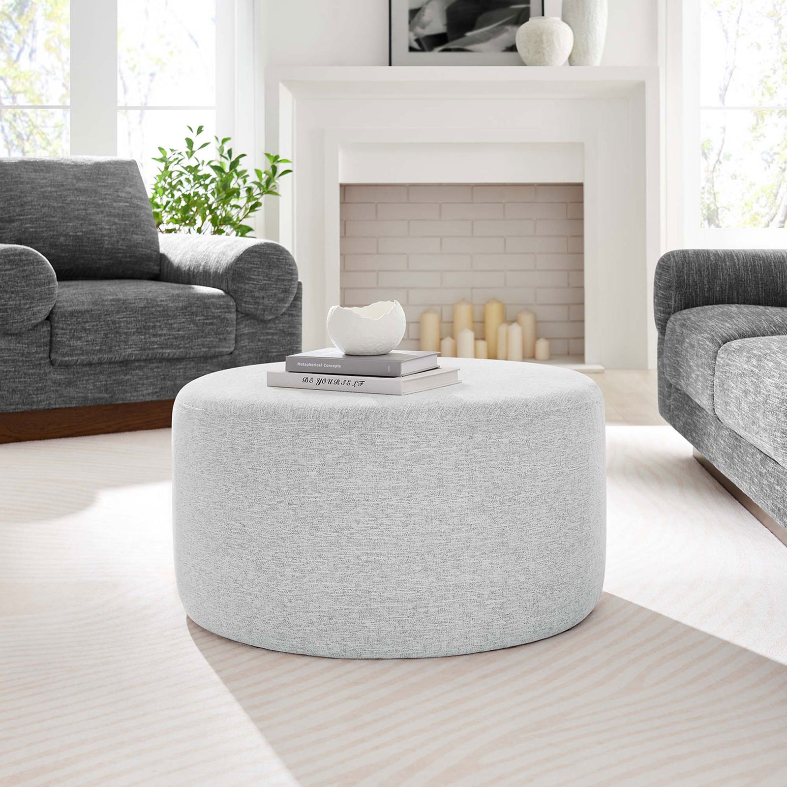 29 inch heathered light gray round ottoman centered in a modern living room between plush sofas || EEI-6647-HLG || front_room