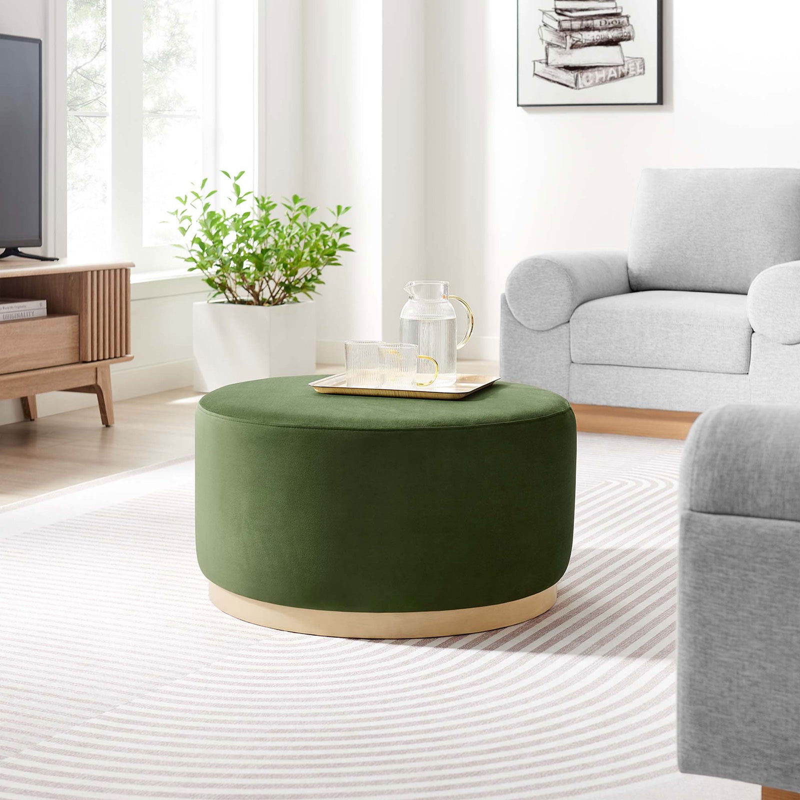 Large moss green velvet round ottoman with wood base anchoring a bright modern living room seating area. || EEI-6648-MOG-NAT || front_angle_room