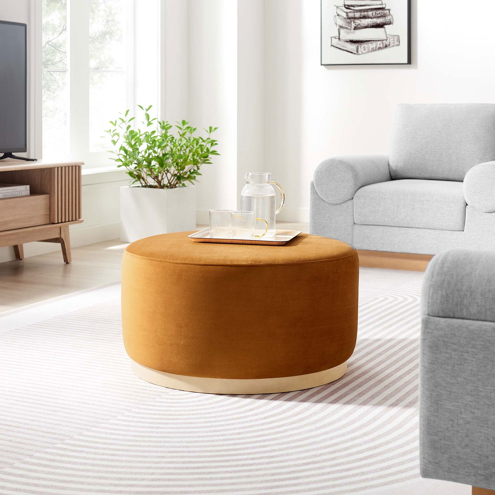 Rust velvet round ottoman with wood base styled in a bright modern living room setting. || EEI-6648-RUS-NAT || front_angle_room