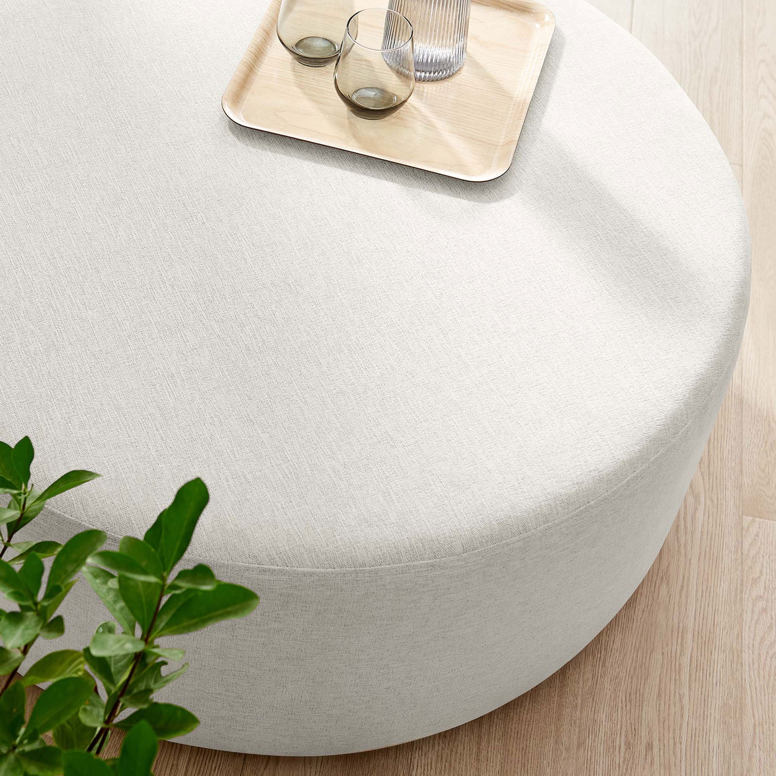 Subtle heathered ivory ottoman top styled with a wood tray, glassware, books, and a fresh green plant. || EEI-6649-HEI || detail_room