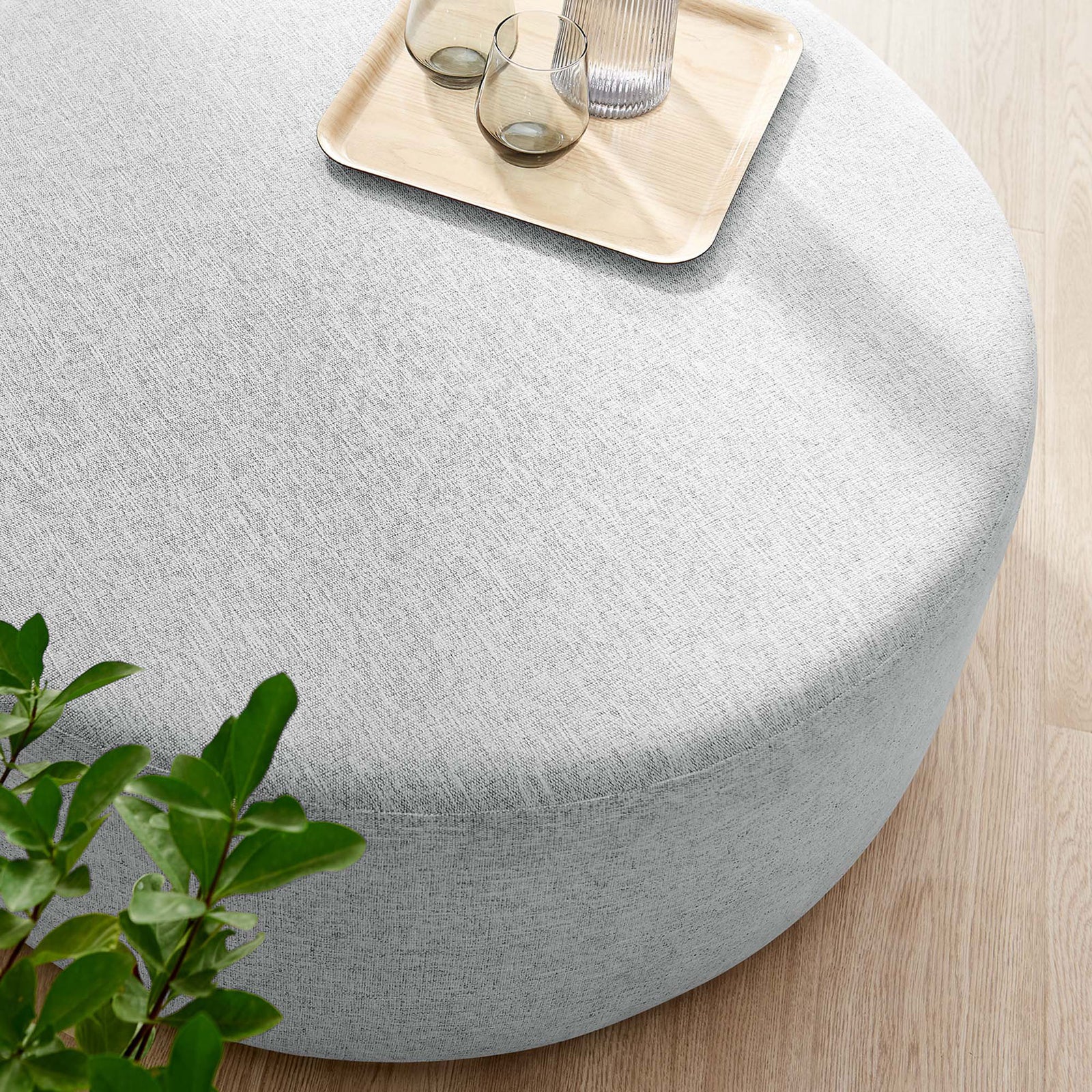 Heathered light gray 38 inch round ottoman styled with a tray, glasses, and decor in a bright room || EEI-6649-HLG || top_room