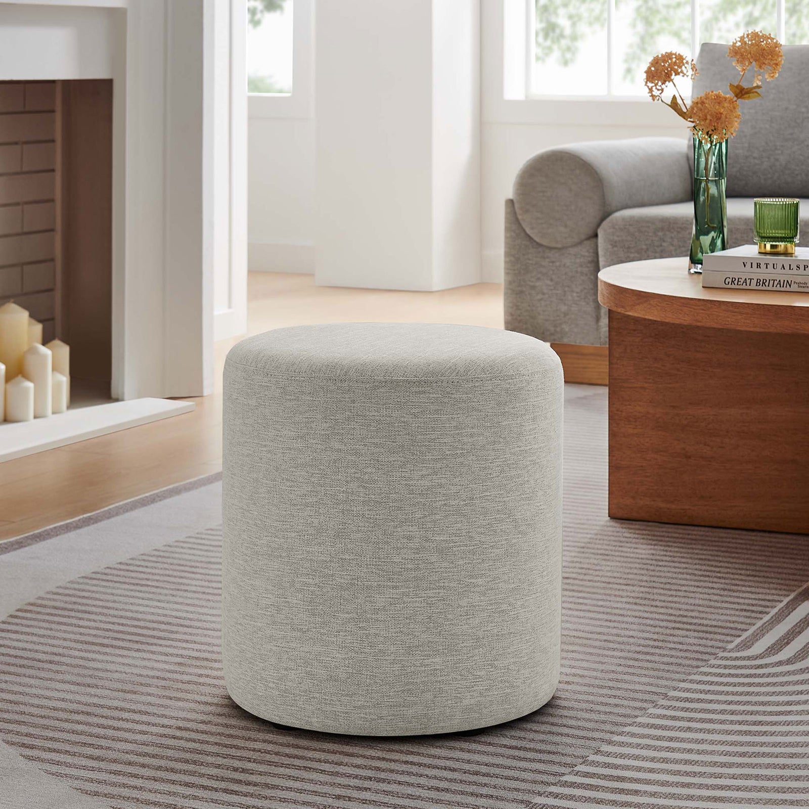 Versatile ivory round ottoman pairs effortlessly with modern seating and a warm wood coffee table. || EEI-6651-HEI || front_angle_room
