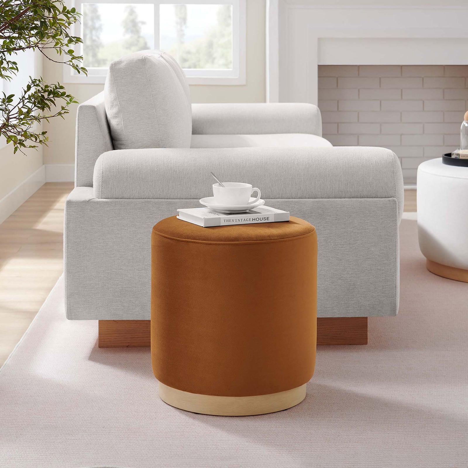 Rust velvet round ottoman with natural wood base adds warm contrast next to a modern light gray sectional || EEI-6652-RUS-NAT || front_angle_room