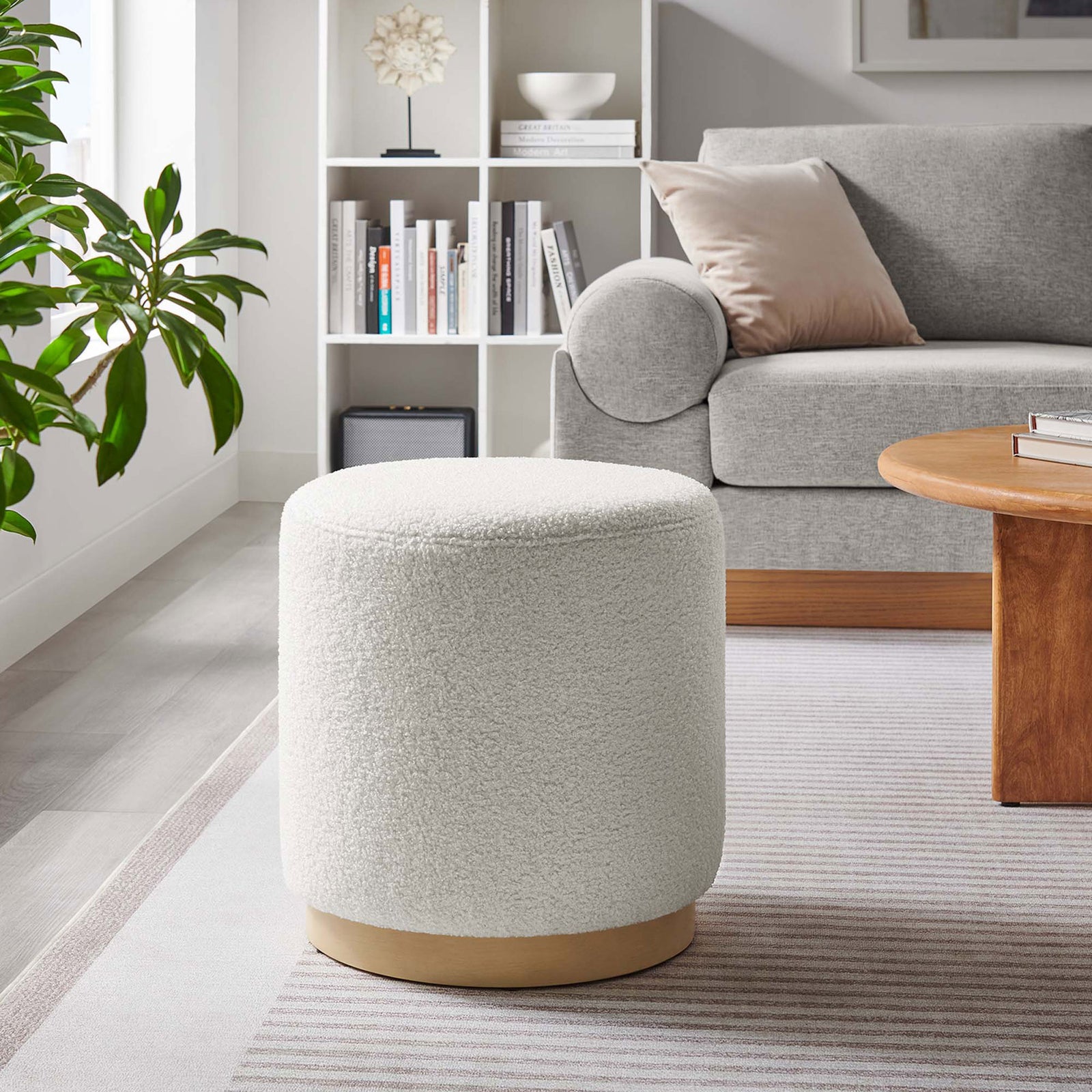 Round ivory ottoman with sherpa upholstery complements contemporary decor and a warm wood coffee table || EEI-6653-IVO-NAT || front_angle_room