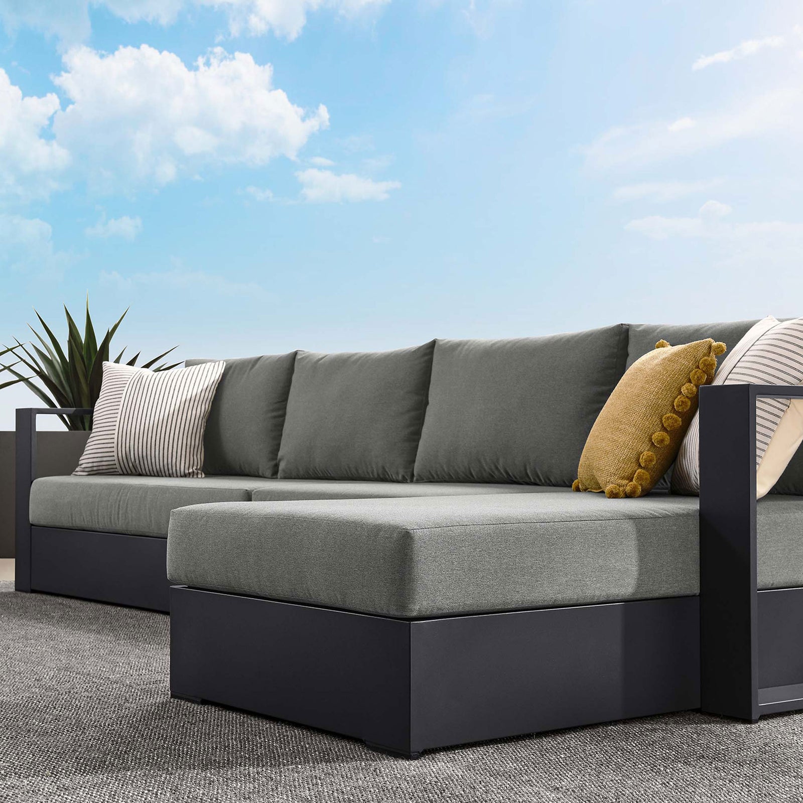 Charcoal chaise end with layered striped and textured pillows creating a relaxed outdoor lounge feel || EEI-6671-GRY-CHA || detail_room