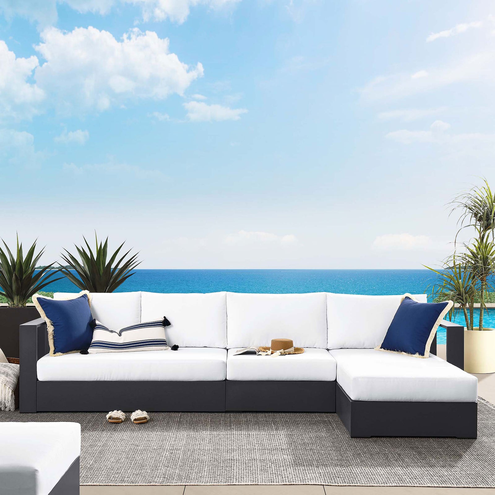 Right chaise sectional on a terrace with ocean view, styled with navy and striped pillows and casual accessories || EEI-6671-GRY-WHI || front_room