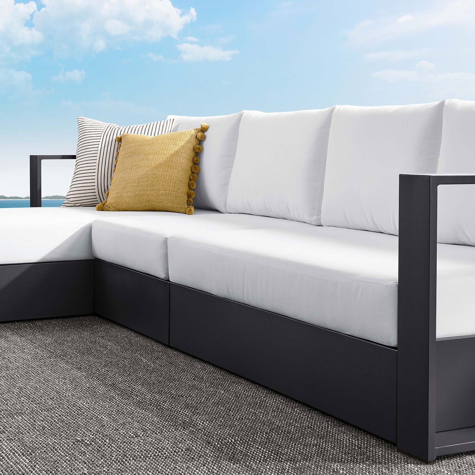 White cushions and armrest of the sectional accented with striped and navy pillows on a patio || EEI-6672-GRY-WHI || detail_room