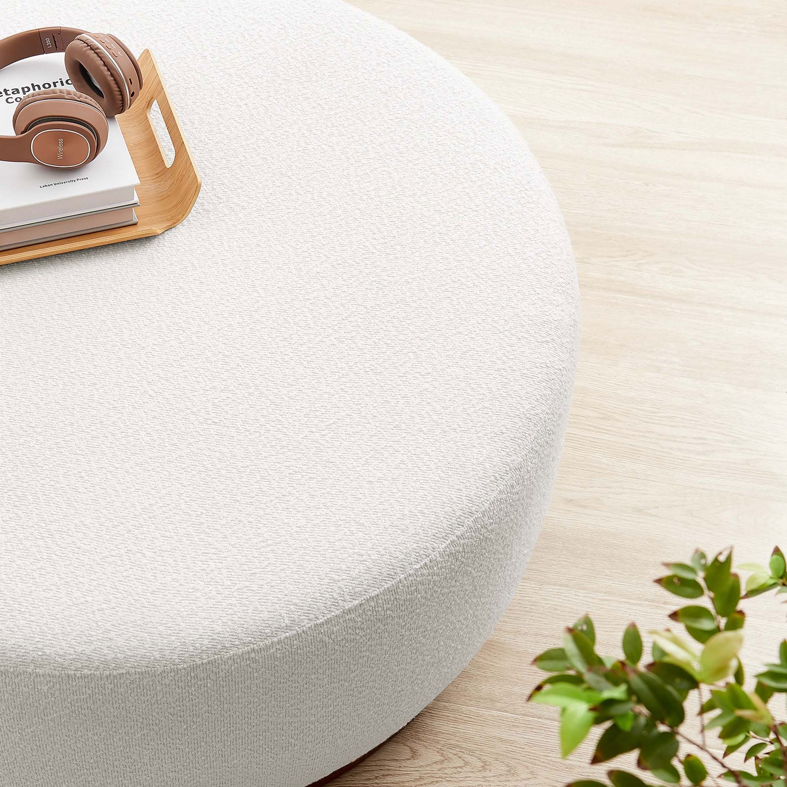 Boucle ottoman surface used as a table for books, tray, and headphones beside greenery || EEI-6682-CLO-WAL || detail_room