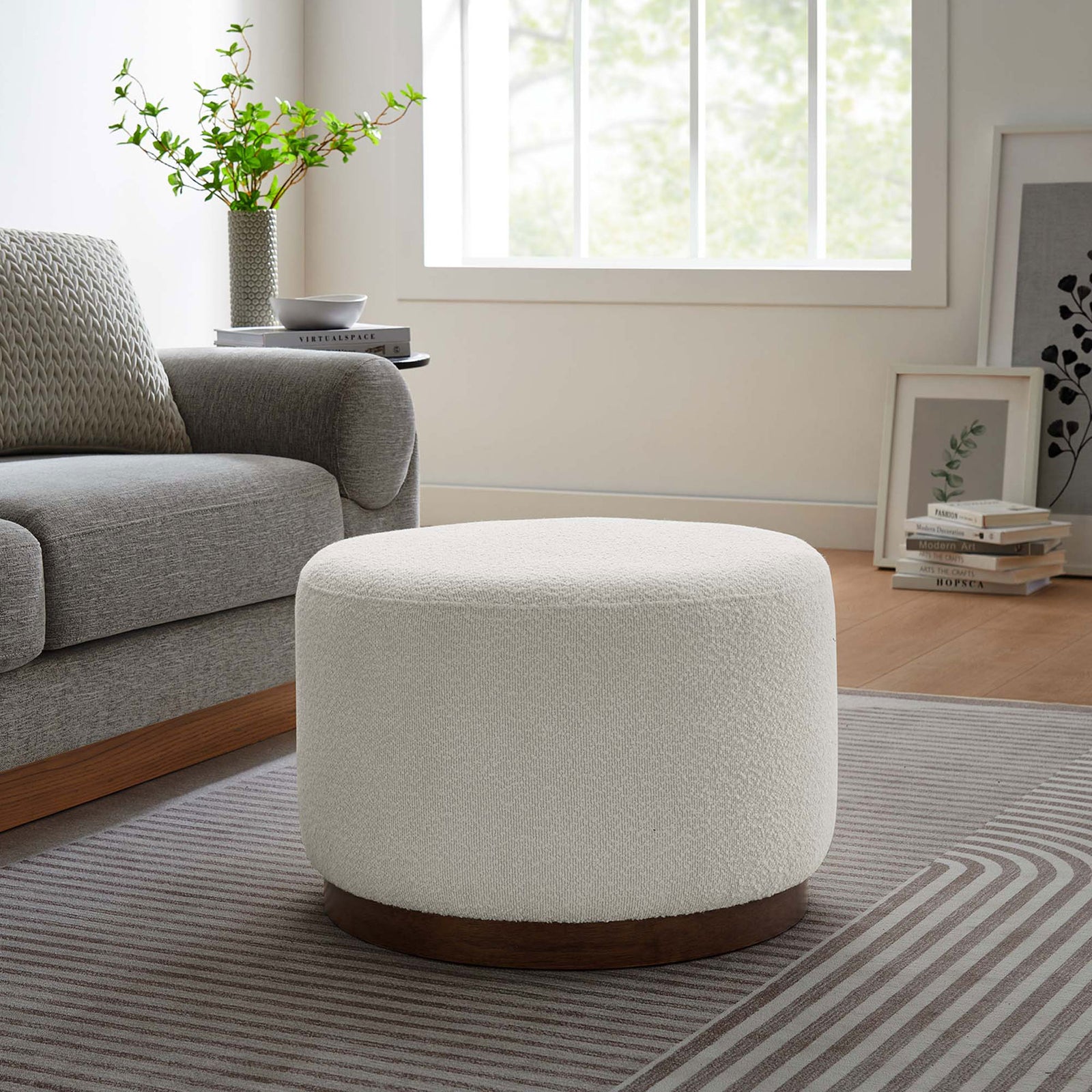 Compact round boucle ottoman with walnut base accenting a modern living room with gray sofa and rug || EEI-6683-CLO-WAL || front_angle_room