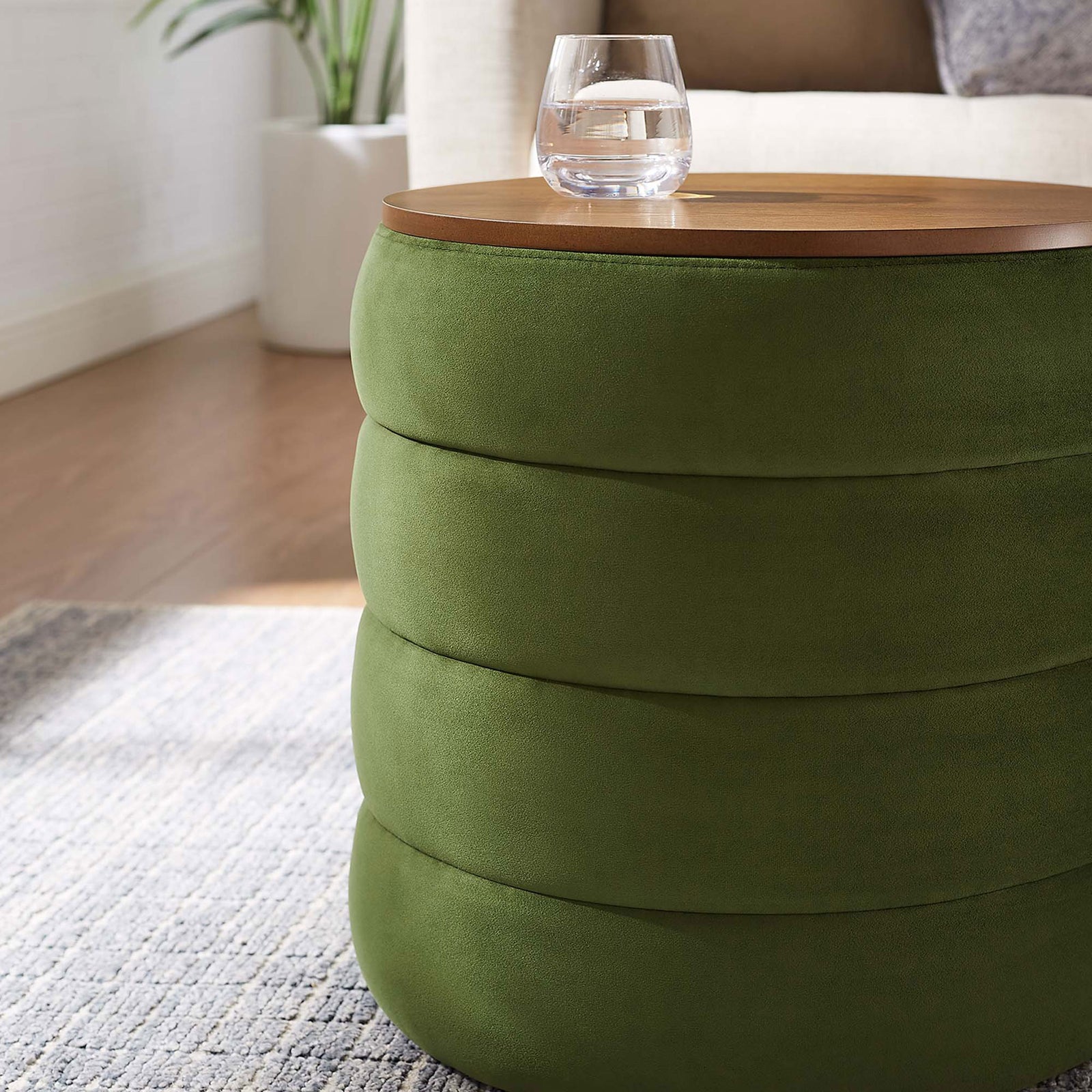 Moss green velvet storage ottoman styled as a side table beside a sofa with a drink resting on the lid || EEI-6684-MOG || detail_room