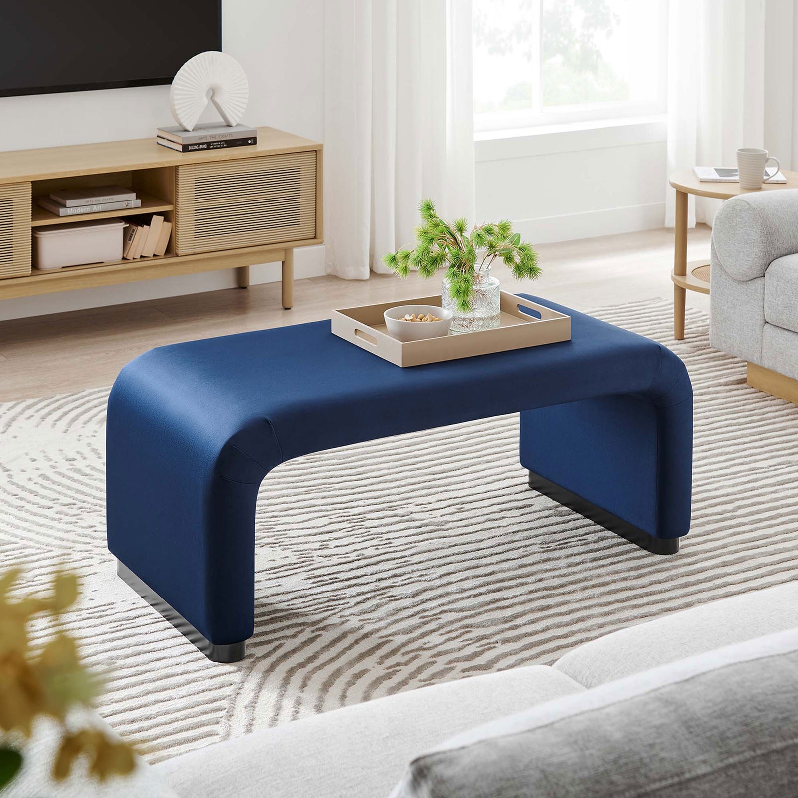Midnight blue waterfall ottoman centered in a modern living room between neutral sofas and textured rug || EEI-6735-BLK-MID || front_angle_room