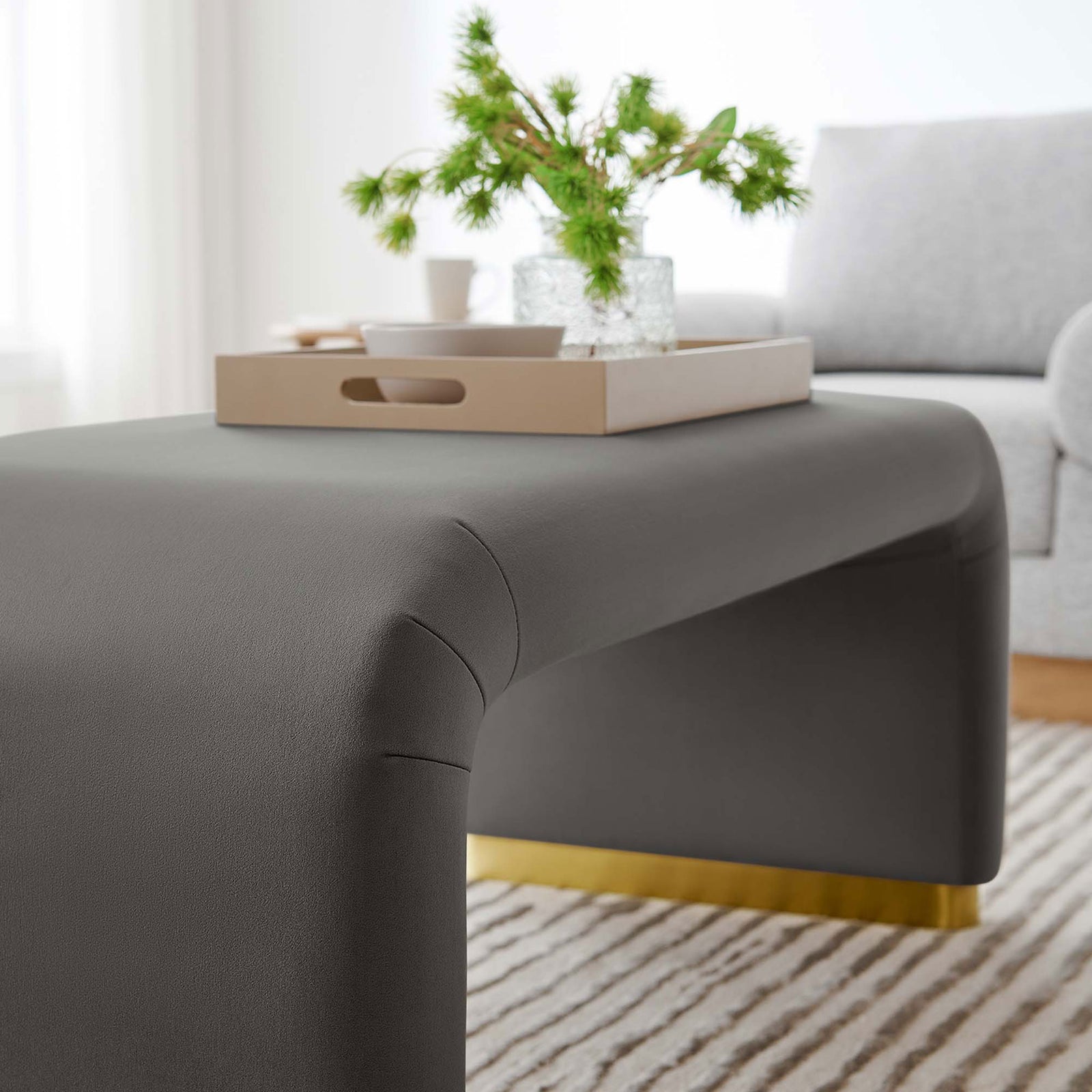Gray velvet waterfall ottoman used as a coffee table with tray and greenery in a cozy living room || EEI-6735-BRA-STG || detail_room