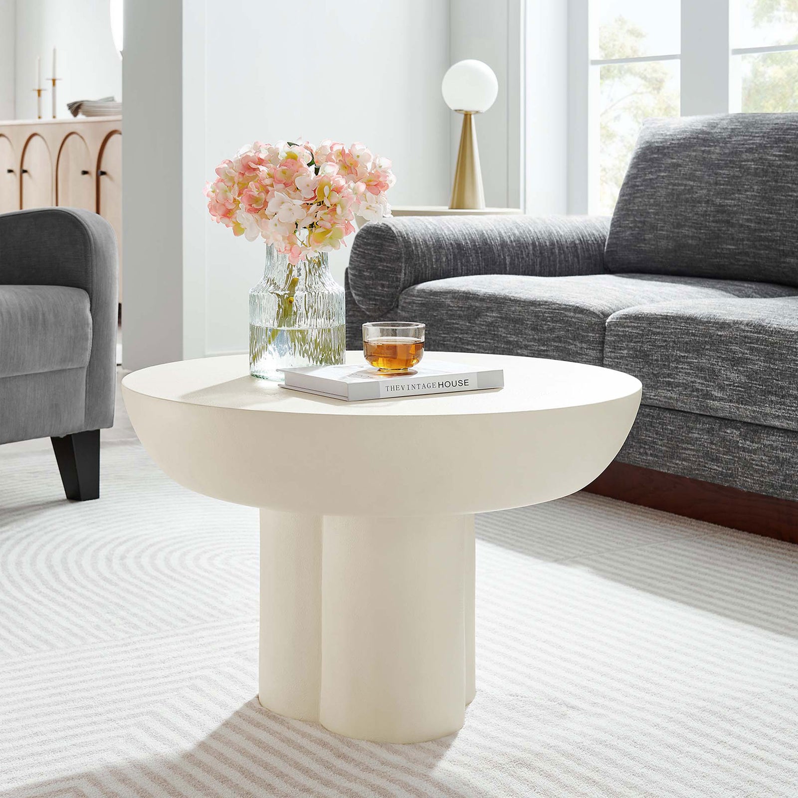 A sculptural white round coffee table adds modern character to a cozy living room setting || EEI-6760-WHI || front_angle_room