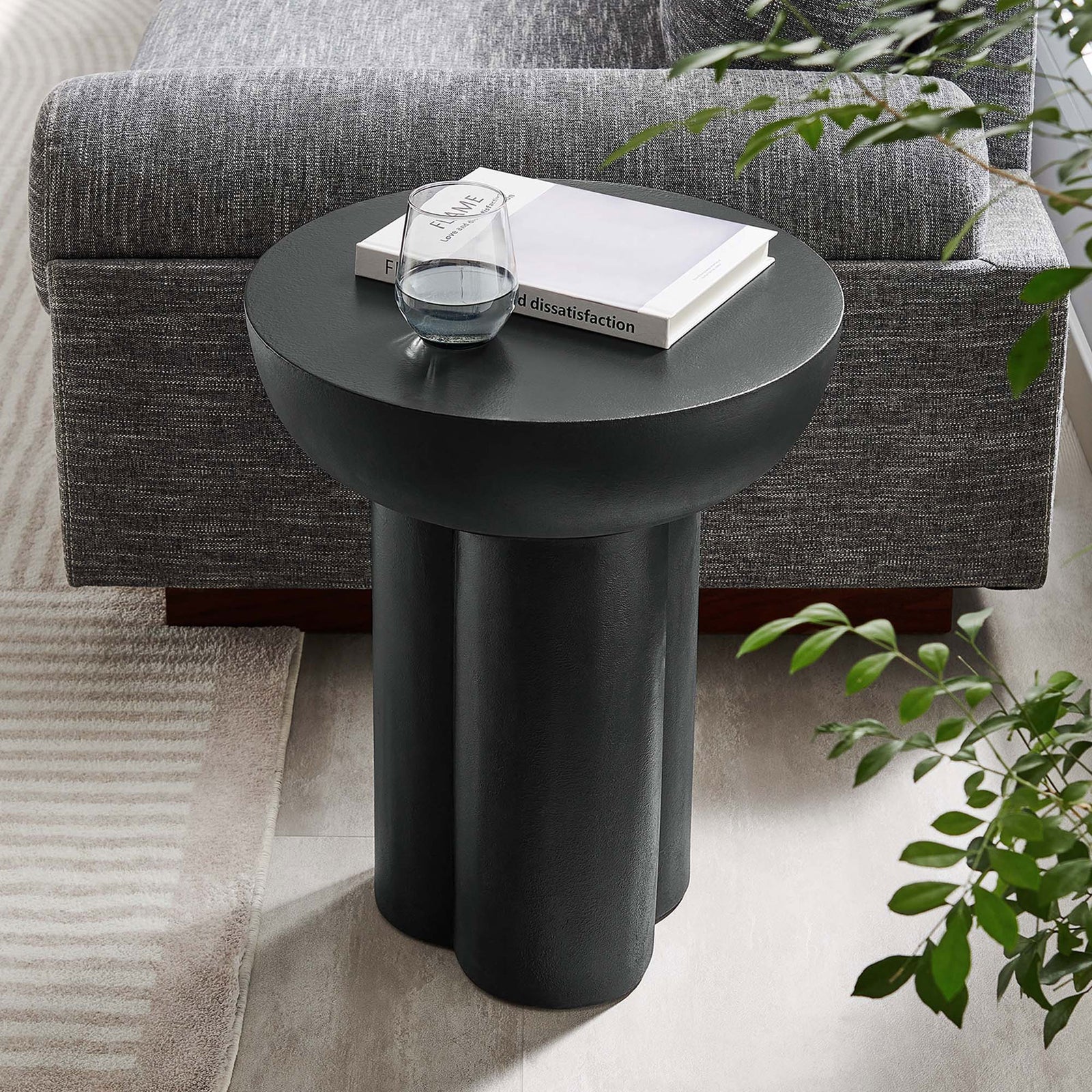 Black round concrete overlay side table next to a sofa, perfect for holding drinks and decor in a modern lounge || EEI-6761-BLK || front_room