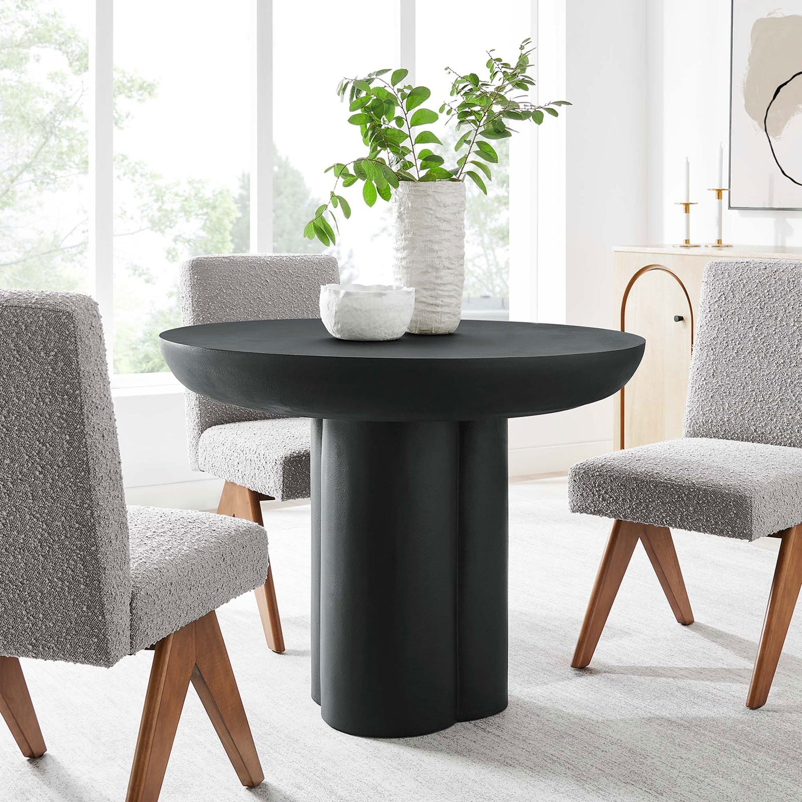 Black round dining table with trefoil base styled with gray chairs in a modern light filled dining room || EEI-6762-BLK || front_angle_room