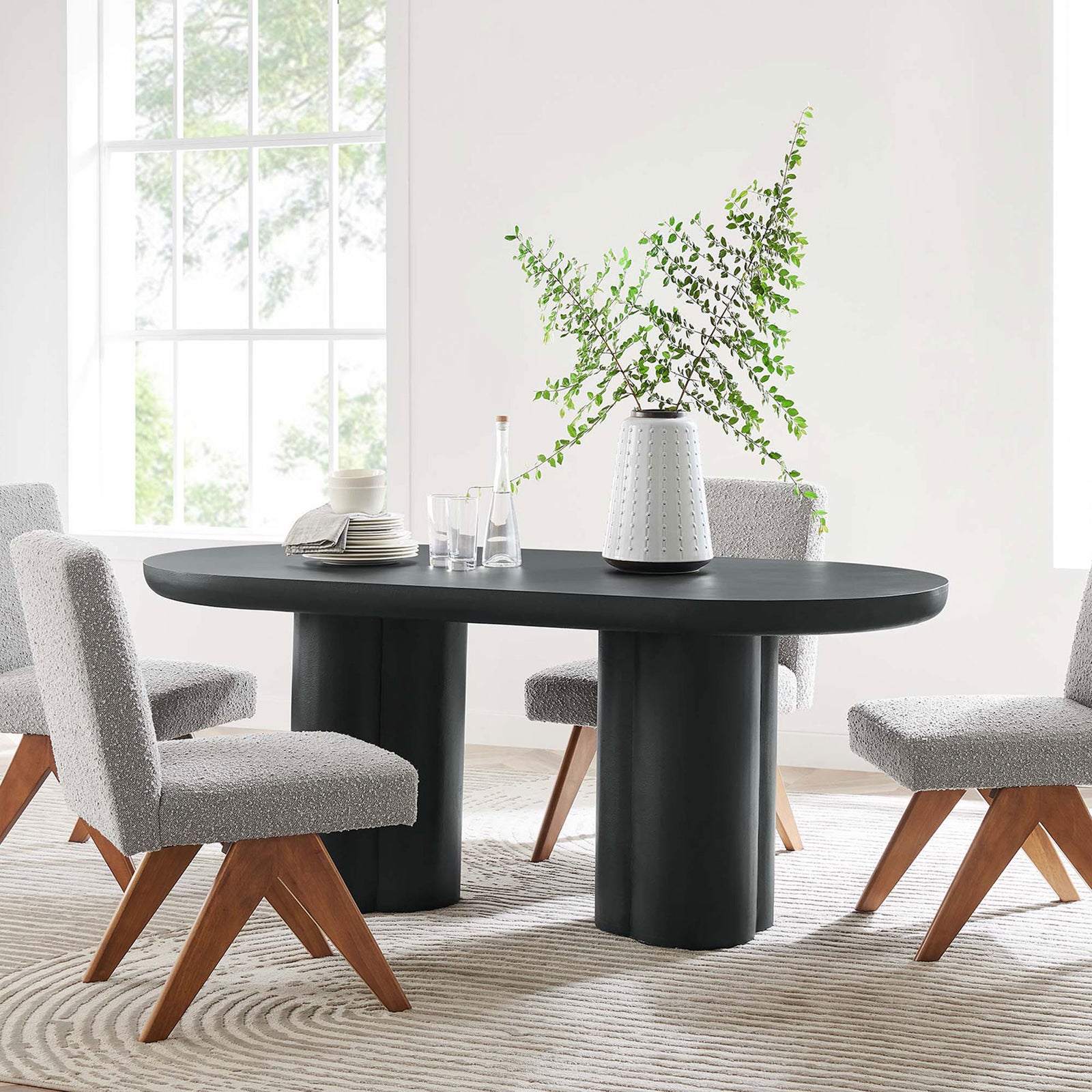 Black oval dining table surrounded by soft textured chairs in a bright airy dining room || EEI-6764-BLK || front_room