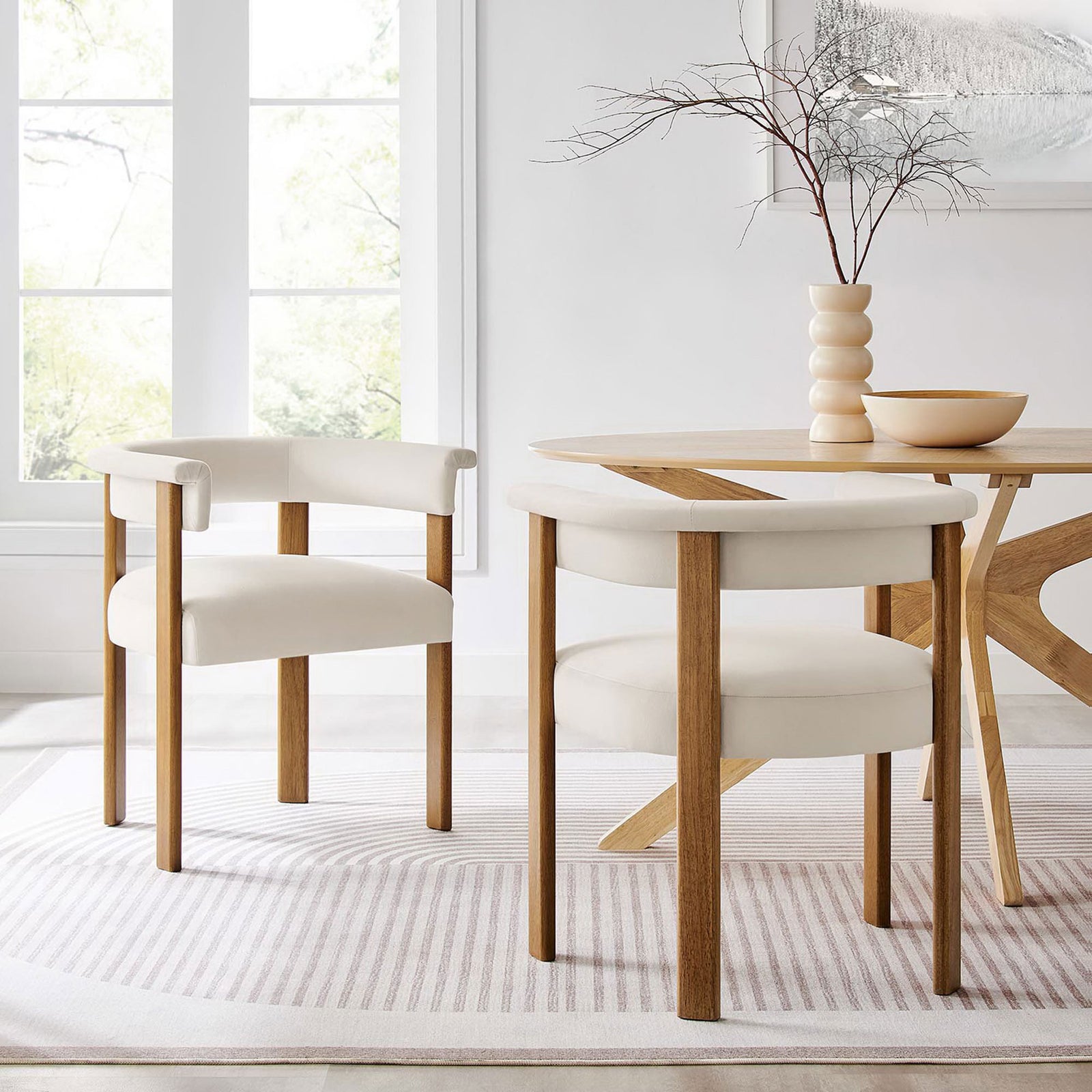 Pair of velvet barrel dining chairs anchor a bright dining nook with sculptural wood table and soft rug. || EEI-6775-ALA-DBR || front_angle_multi_room