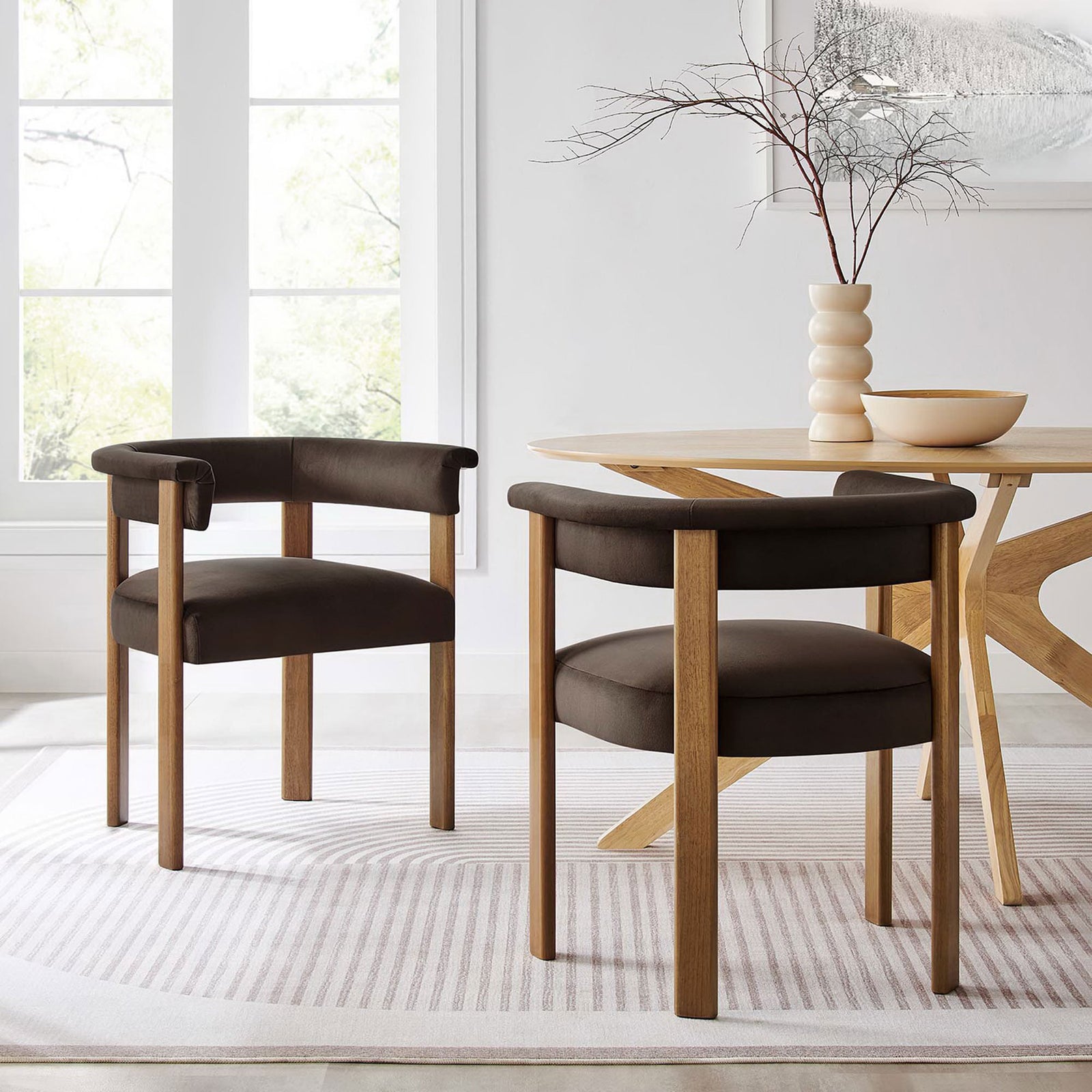 Pair of chocolate brown velvet barrel dining chairs around a modern dining table on a patterned rug || EEI-6775-CHB-DBR || front_angle_multi_room