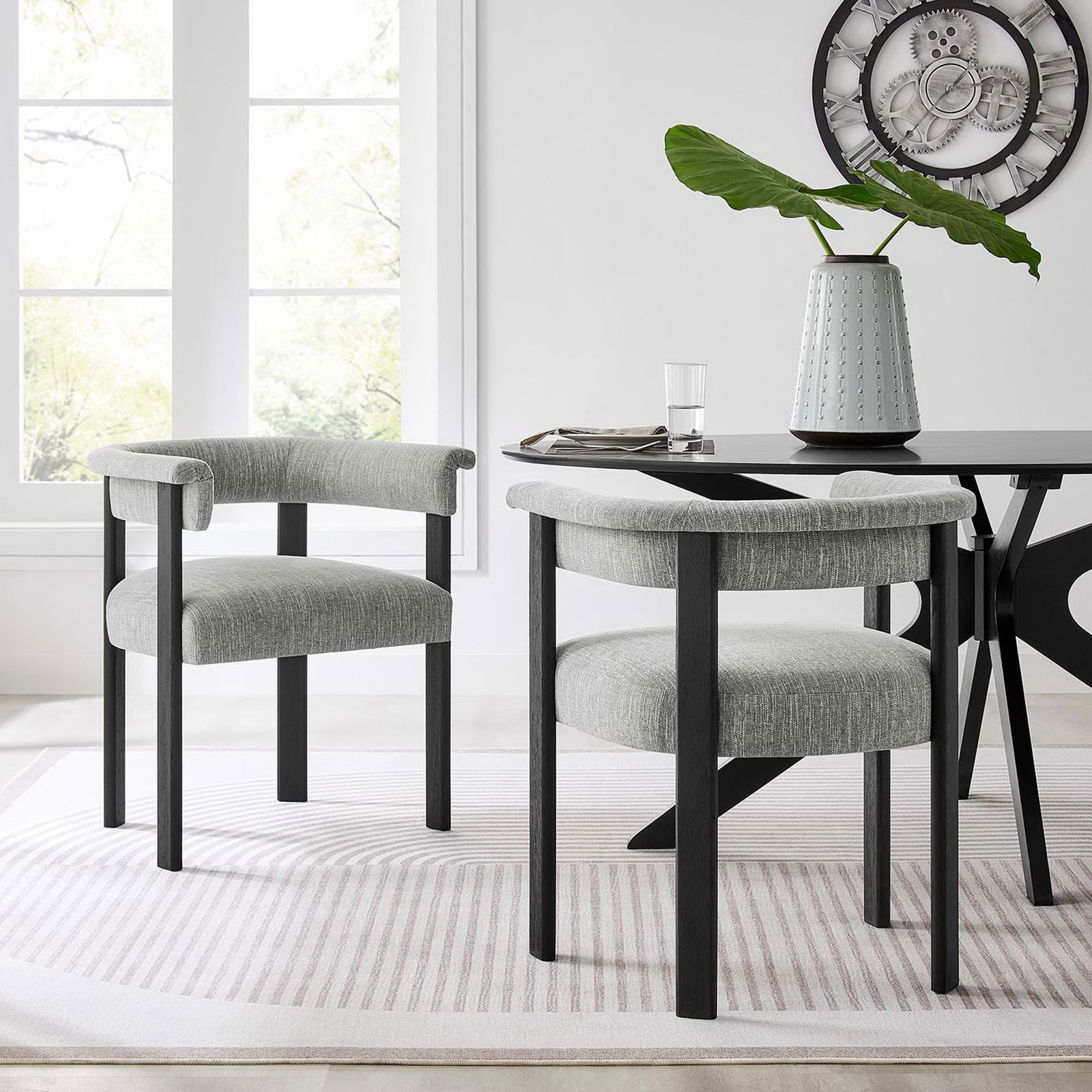 Pair of Imogen barrel dining chairs anchors a contemporary dining area with warmth and understated luxury || EEI-6776-HEG-BLK || front_angle_multi_room