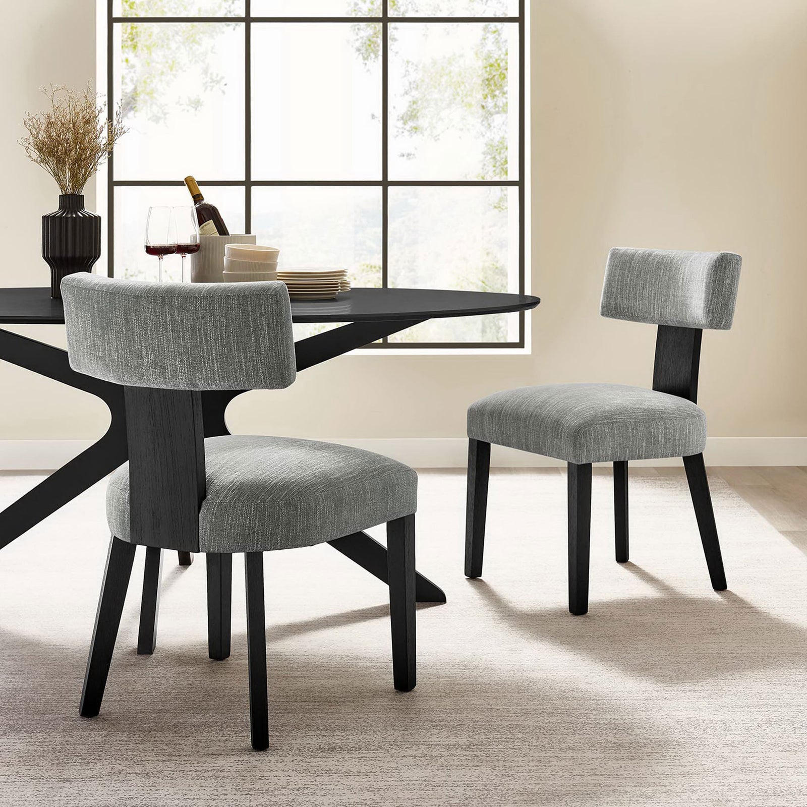 Pair of gray fabric dining chairs around a modern black dining table in a bright airy room || EEI-6777-HEG-BLK || front_angle_multi_room