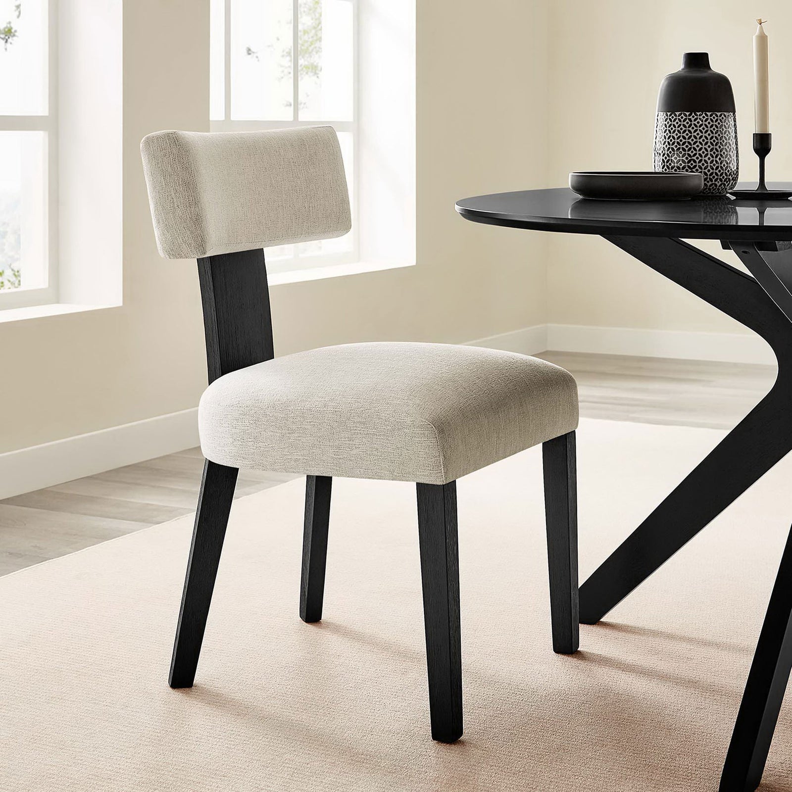 Ivory dining chair with black wood legs styled beside a modern round table in a bright room || EEI-6777-HEI-BLK || front_angle_room