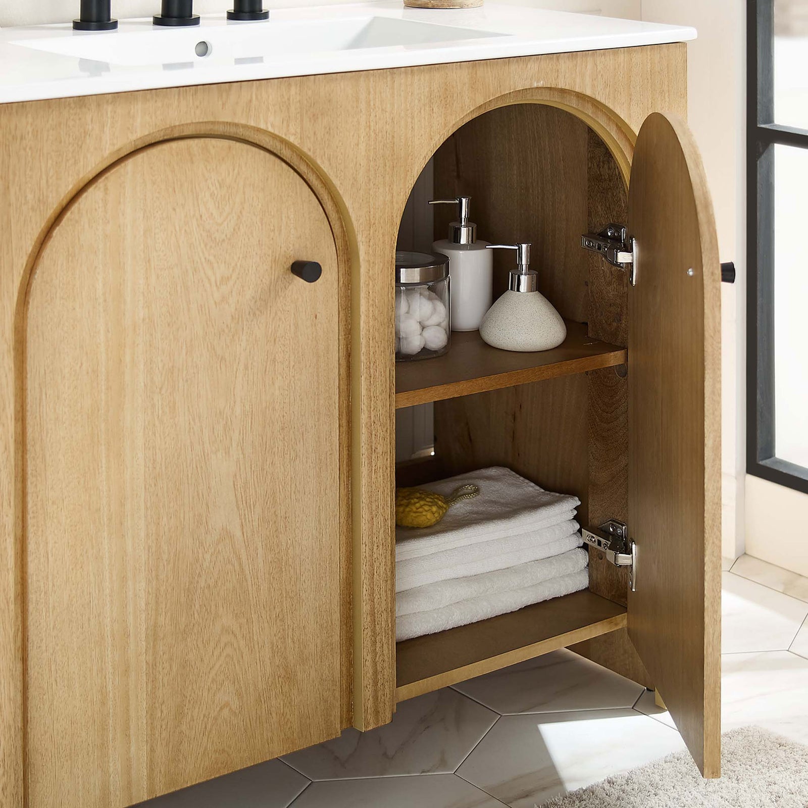 Spacious interior with adjustable shelf neatly organizes towels and essentials behind arched doors. || EEI-6790-OAK-WHI || storage_open_room