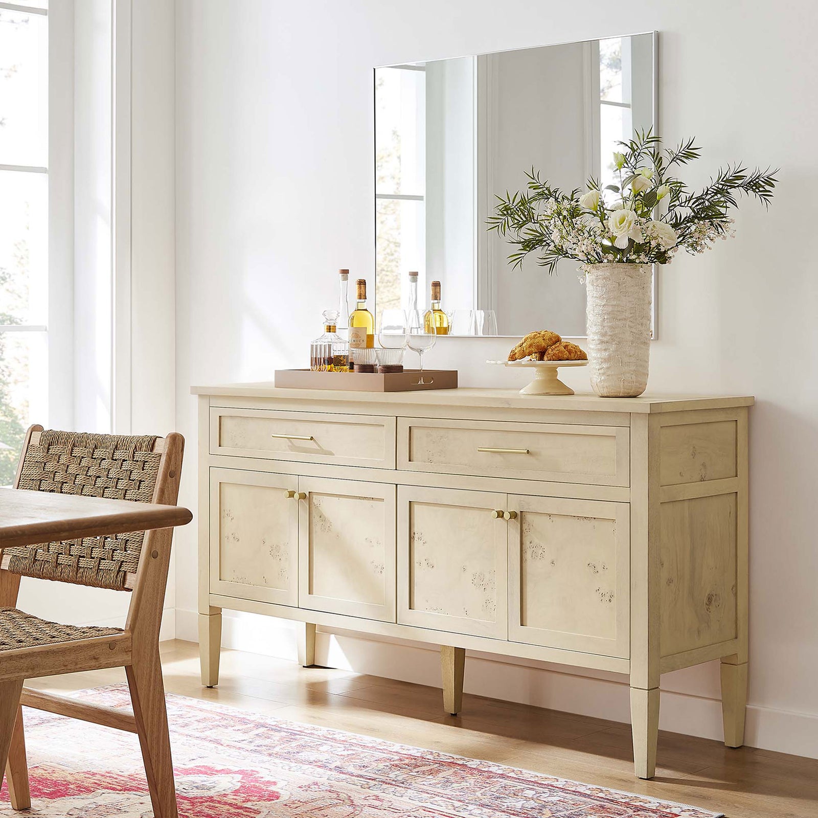 Elysian burl wood sideboard in a dining space, topped with vase, mirror, and decor for an inviting entertaining area || EEI-6794-BUR || front_angle_room